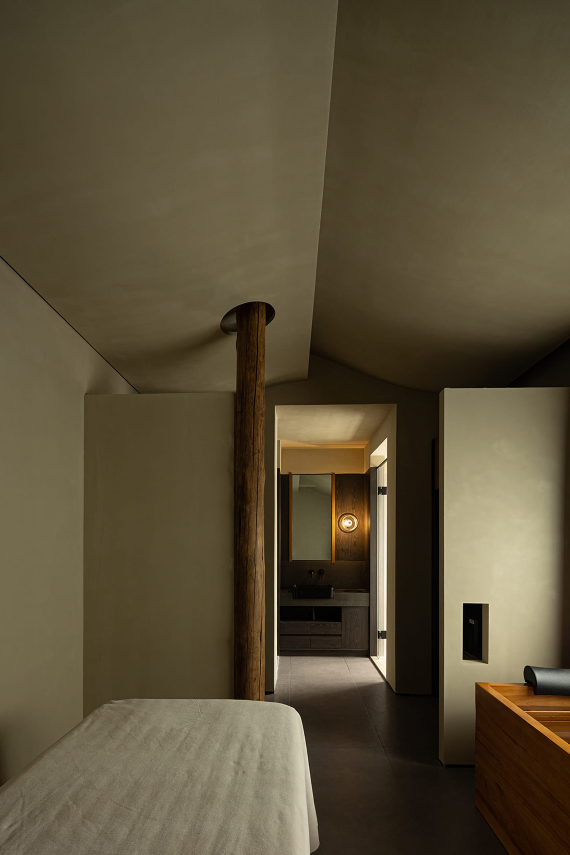 A minimalist bedroom with concrete walls and a bed.