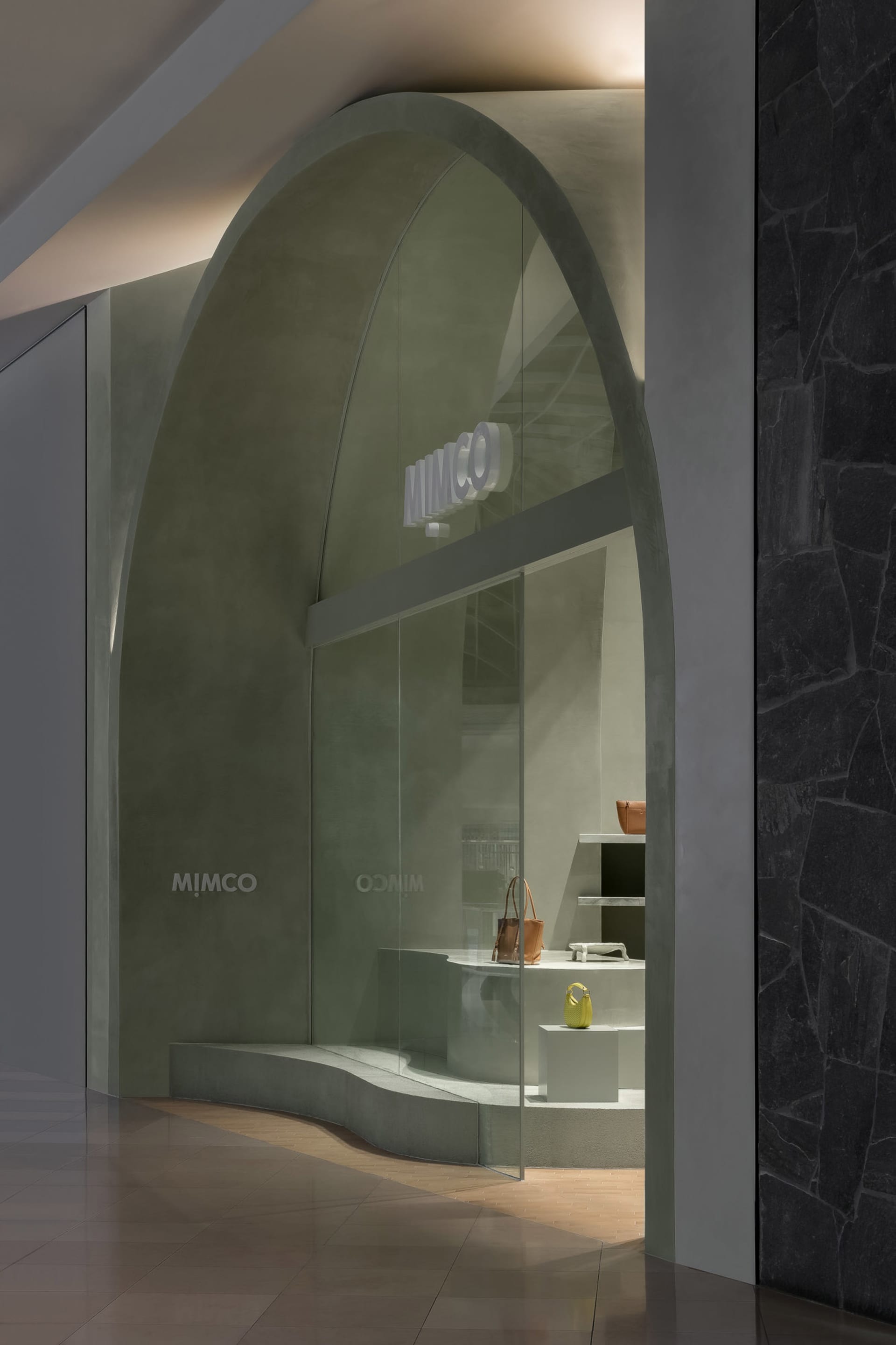 現代極簡店面,拱形混凝土入口搭配玻璃櫥窗,展示手提包。