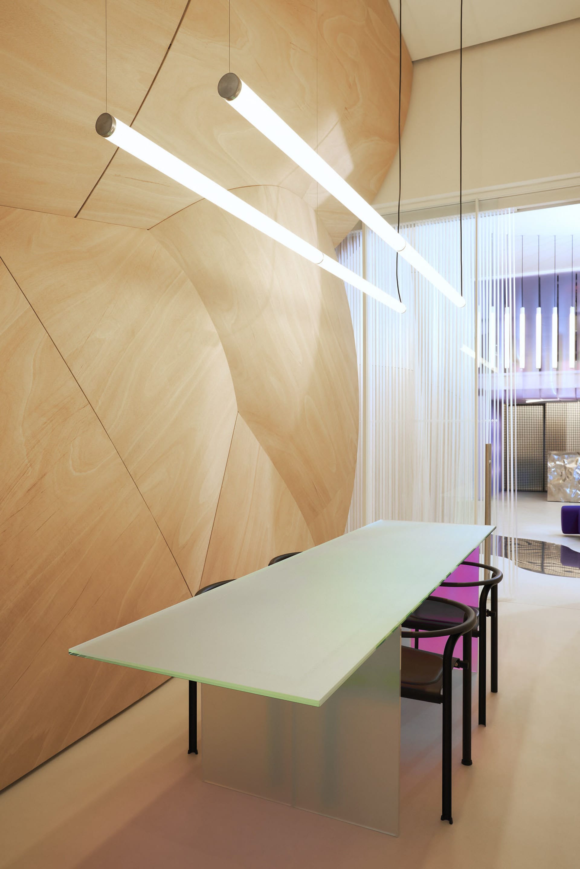 Modern conference room with glass table and minimalist lighting.