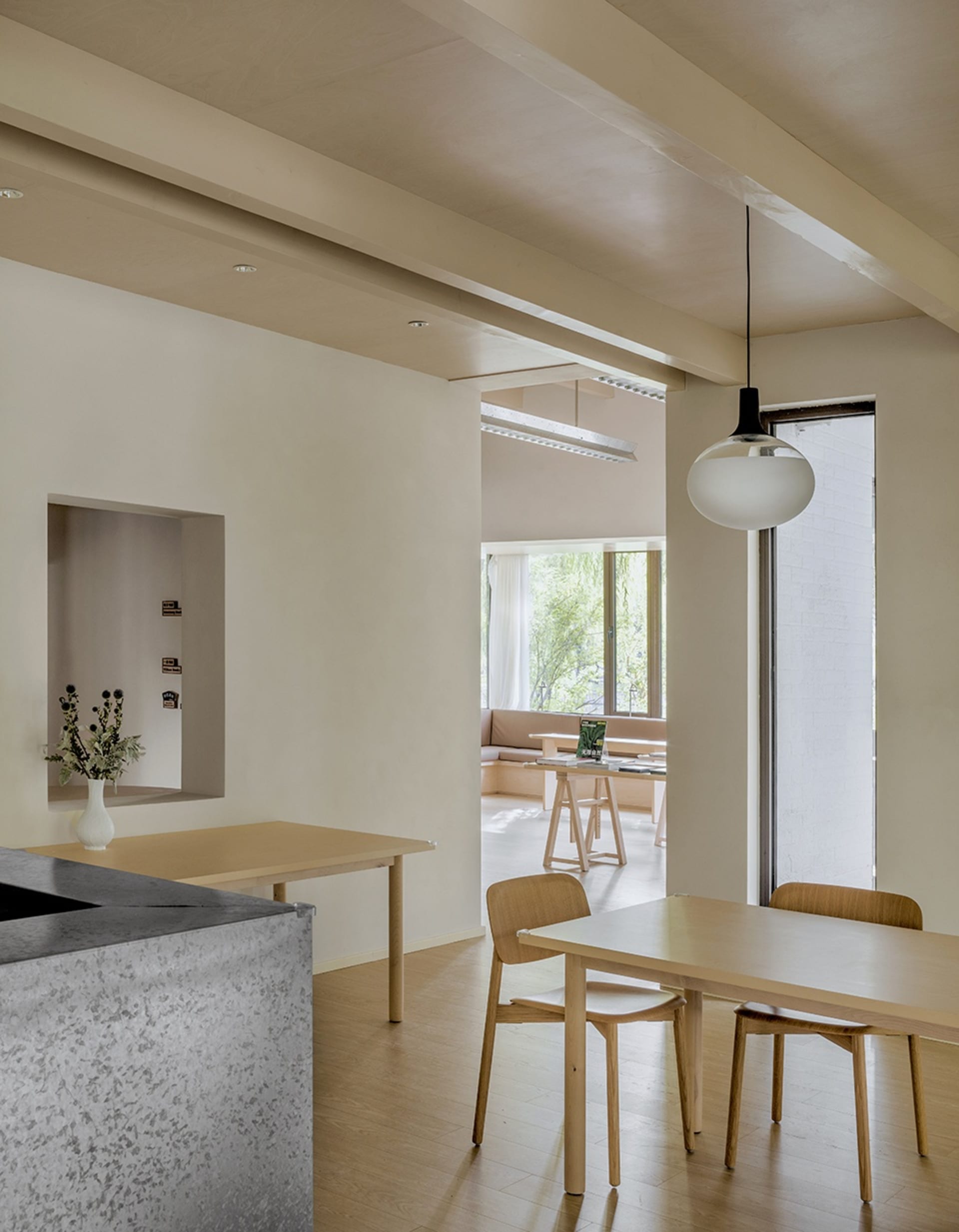 Modern residential living room with wooden furniture and a concrete wall, featuring shadows and natural light.