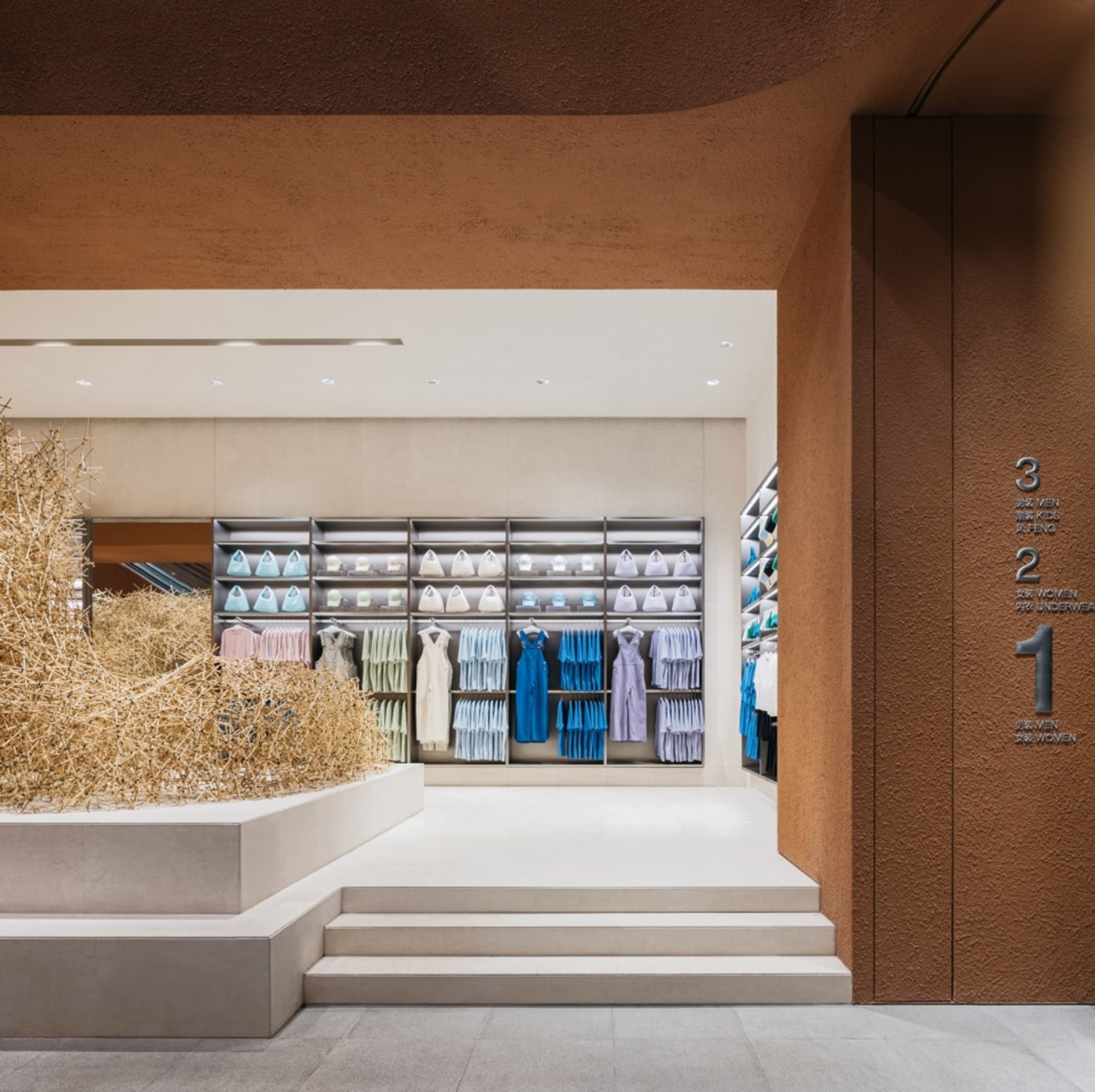 現代零售店面，混凝土牆面搭配展示的白色、粉彩與藍色服裝。