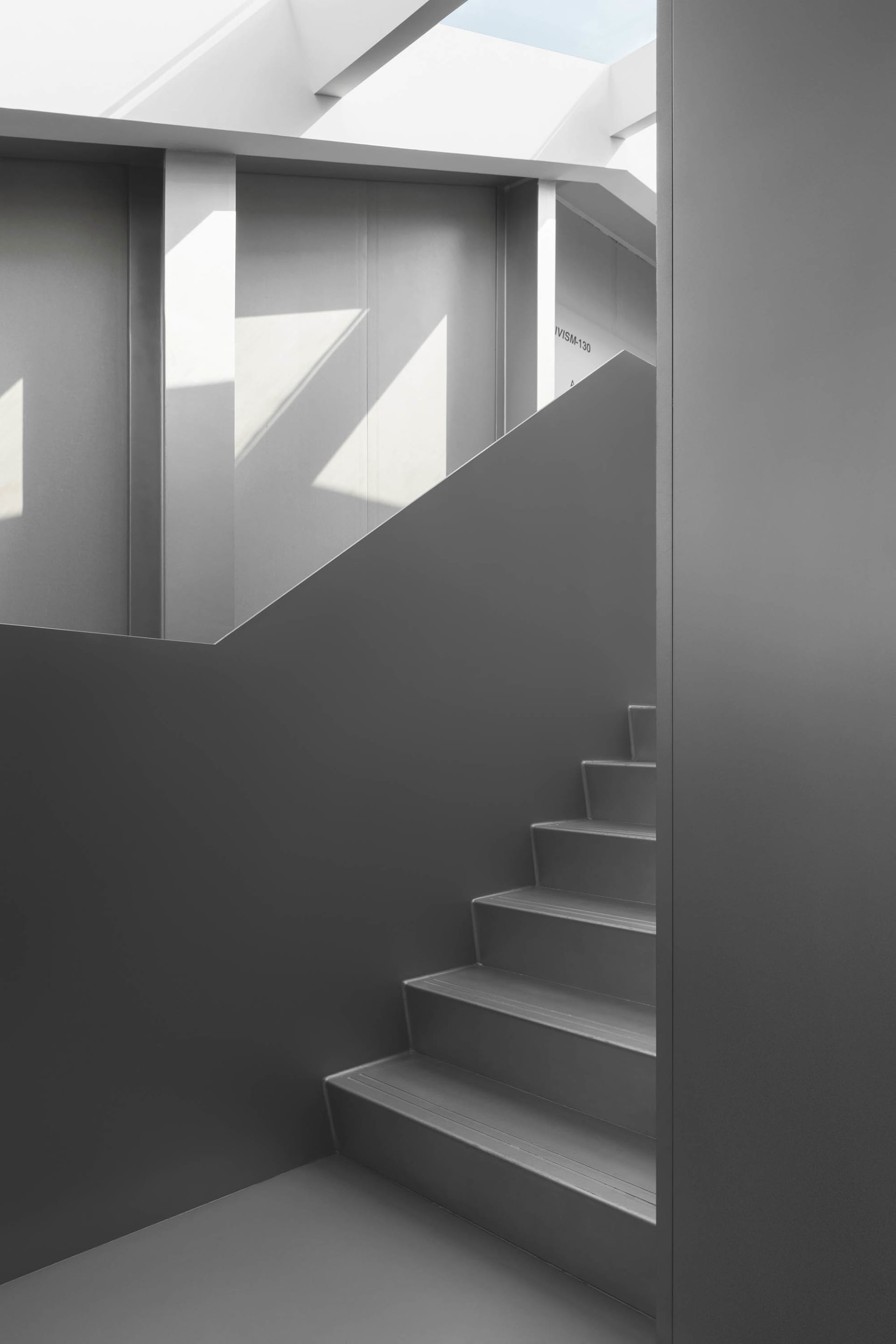 Gray concrete staircase with light shining through a skylight.