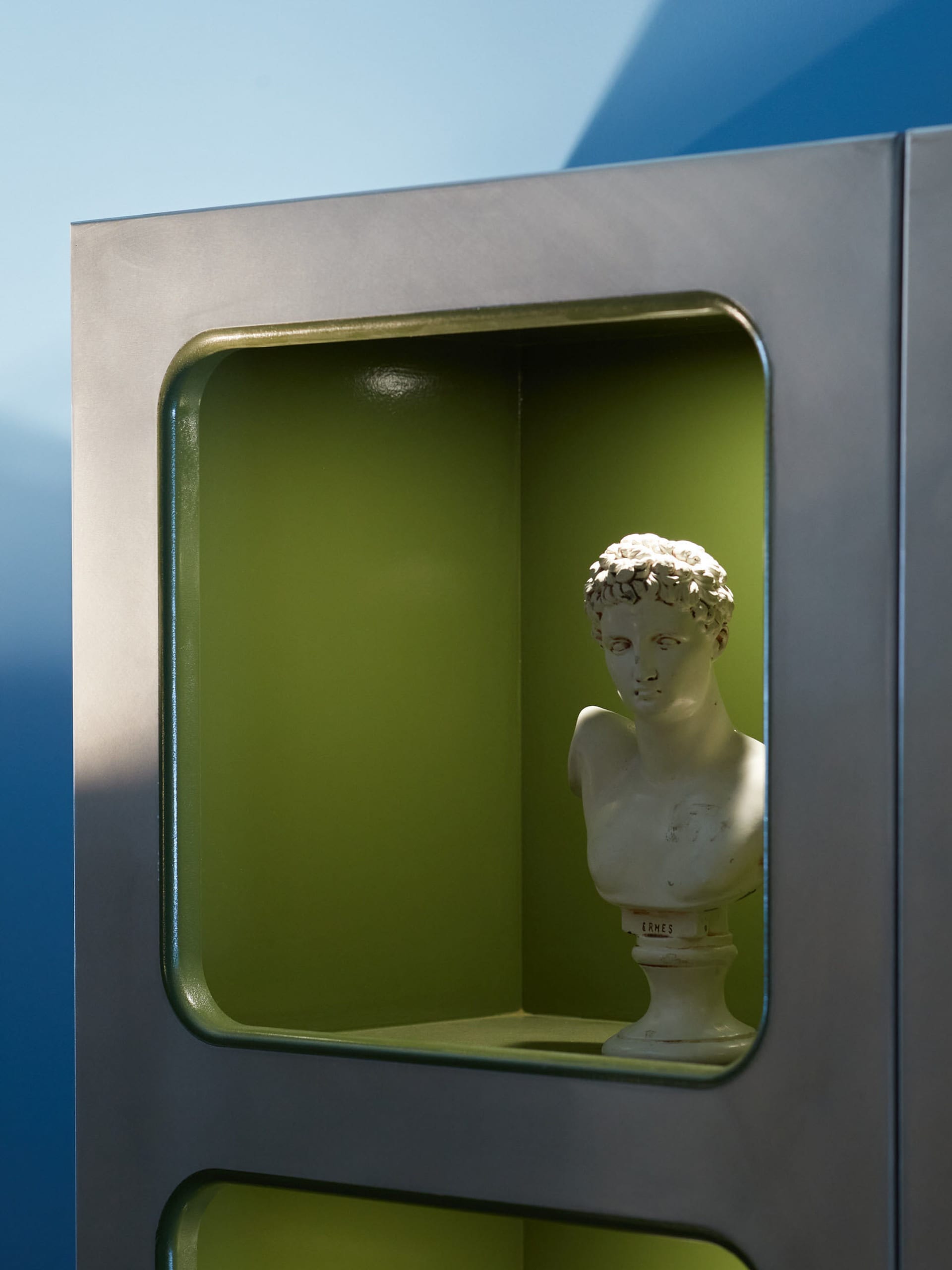 A statue of a person with curly hair displayed in a minimalist setting.