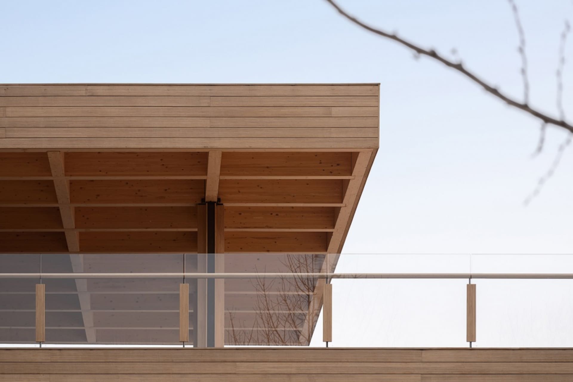 A modern residential exterior featuring wooden beams against a clear sky.