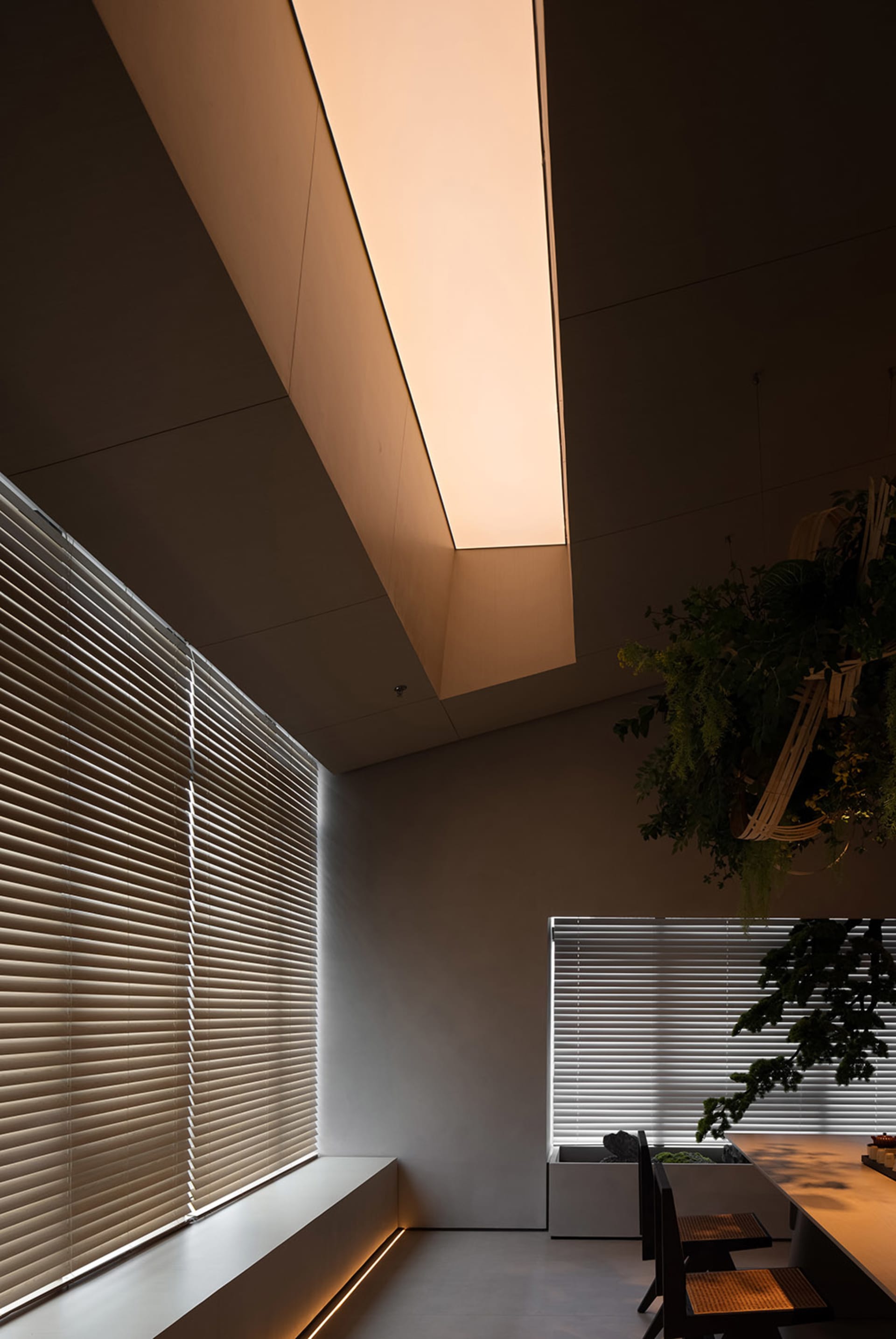 A modern dining room with metallic blinds and green plants
