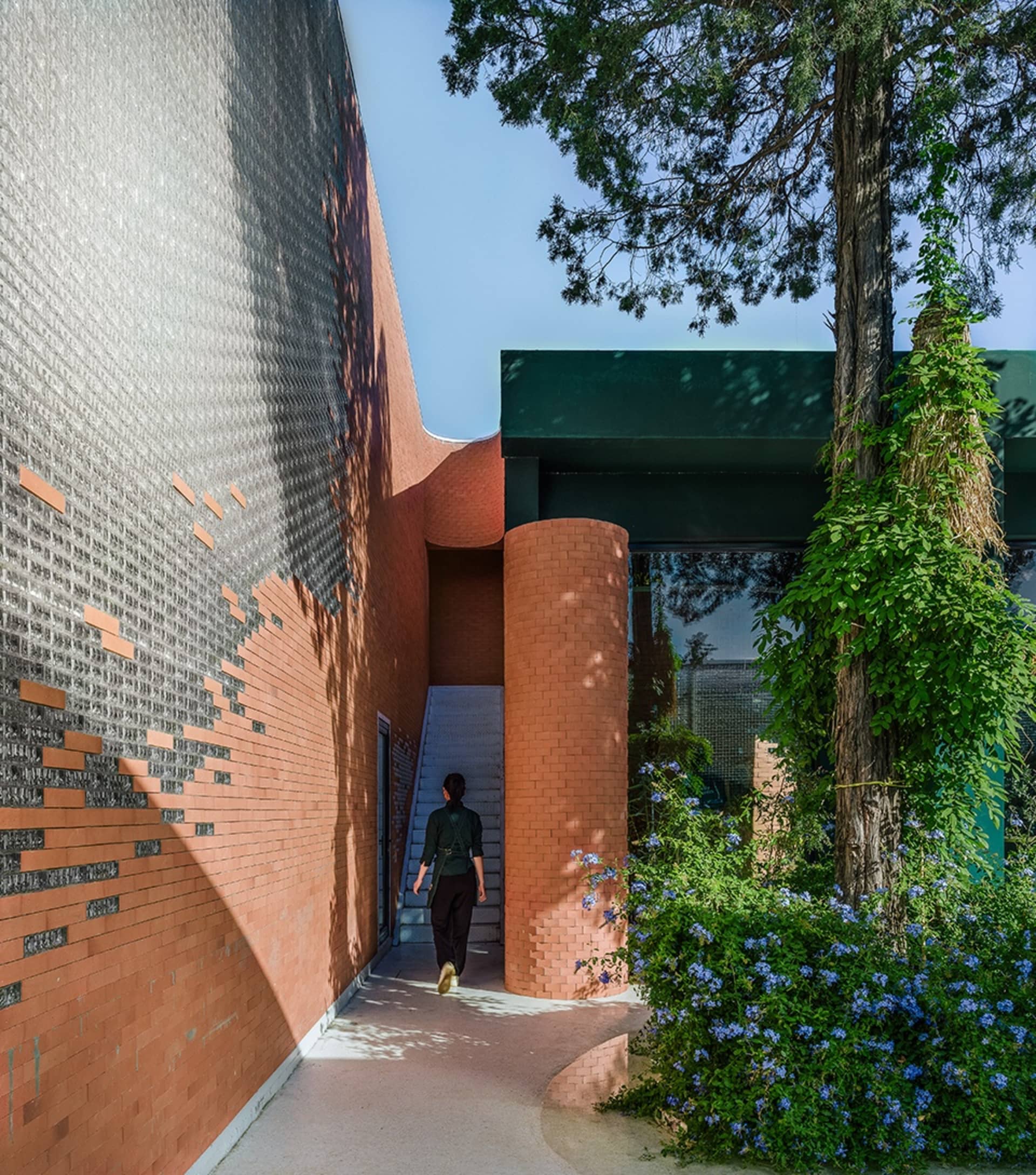 A modern exterior entryway featuring brick and concrete materials, with a person walking through the entrance.