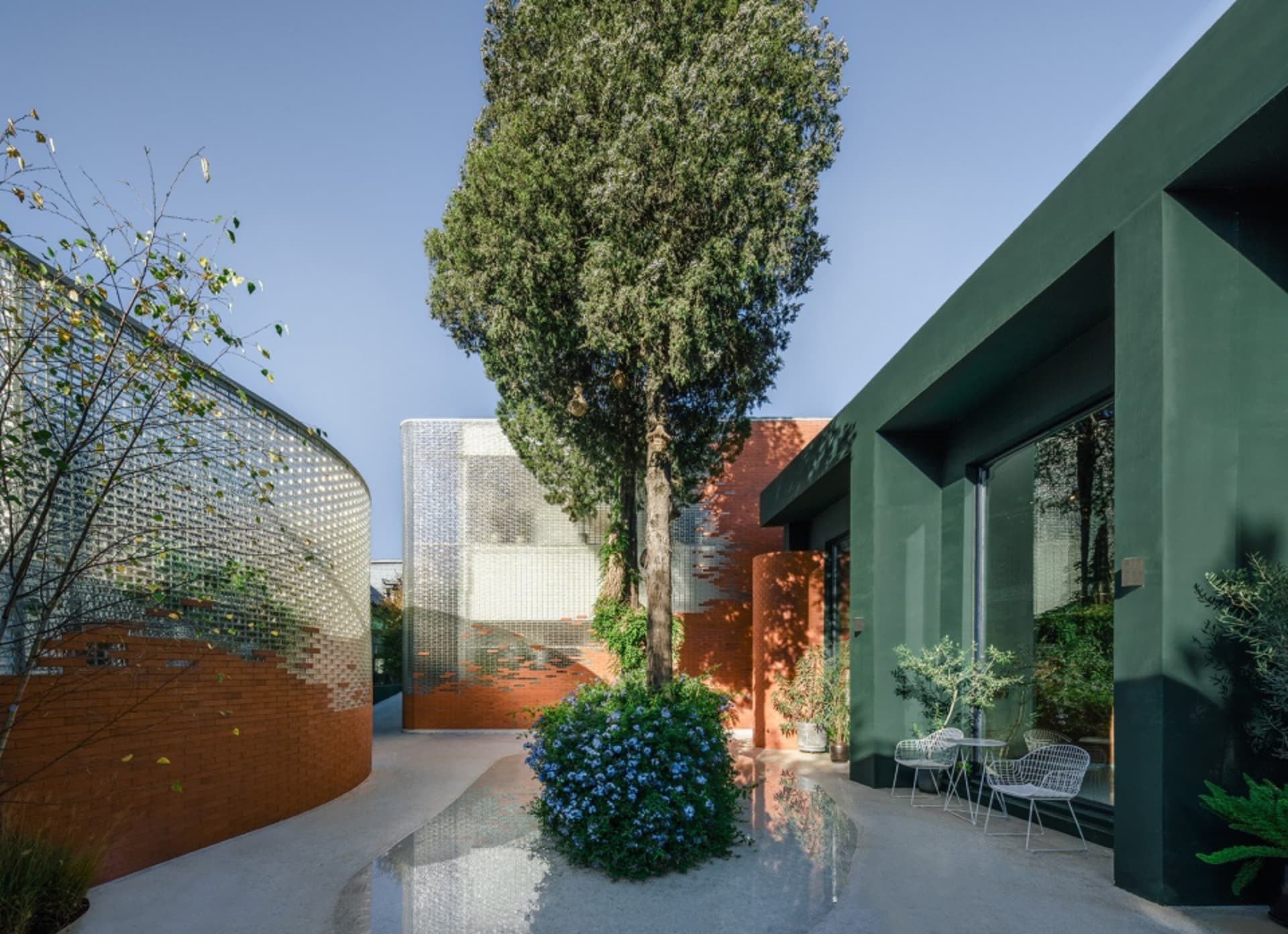 A modern residential exterior with glass and brick walls and concrete ground.