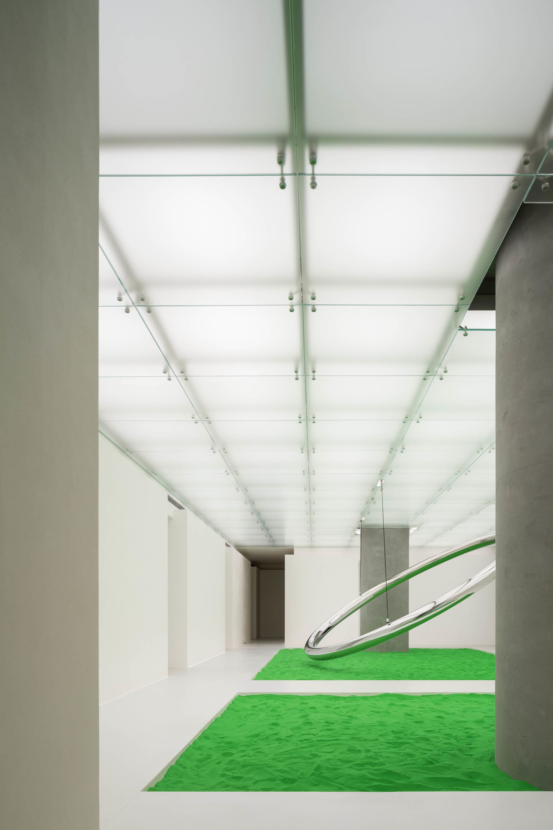 Modern empty white hallway with green rug and glass ceiling and floor.