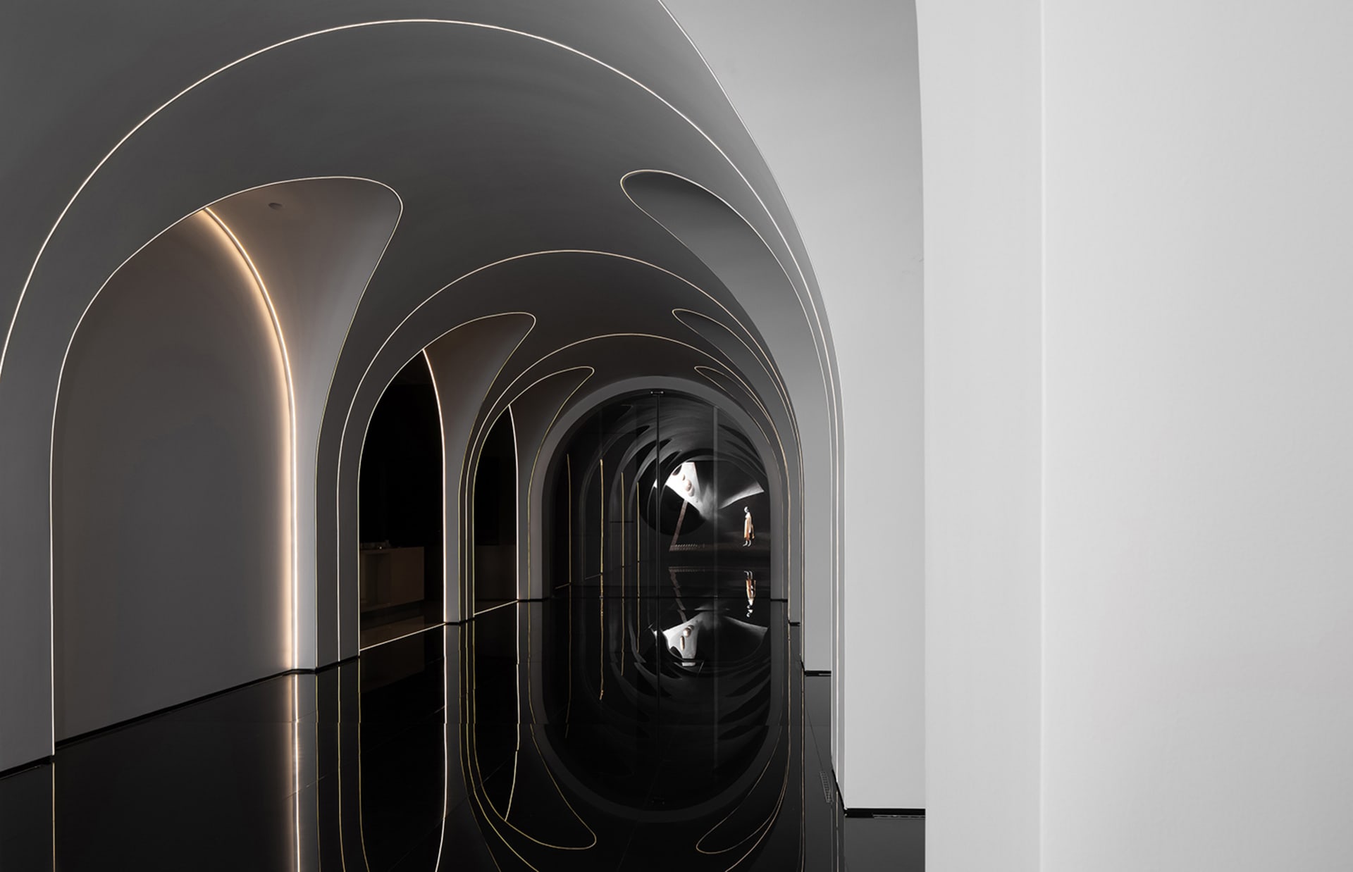 A minimalist, black and white architectural interior with curved glass walls and a reflective floor.