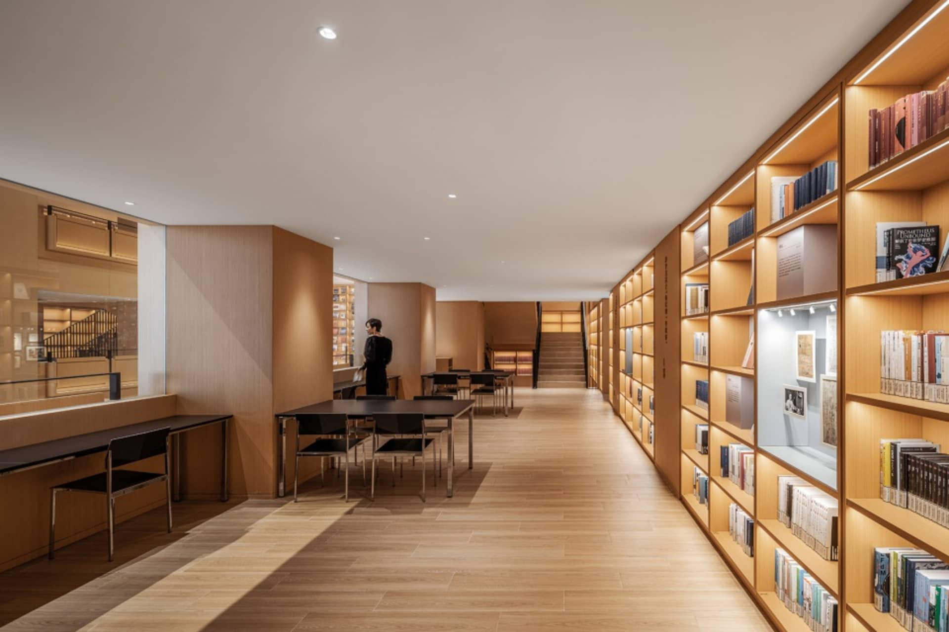 Industrial-style library interior with wooden shelves and tables.