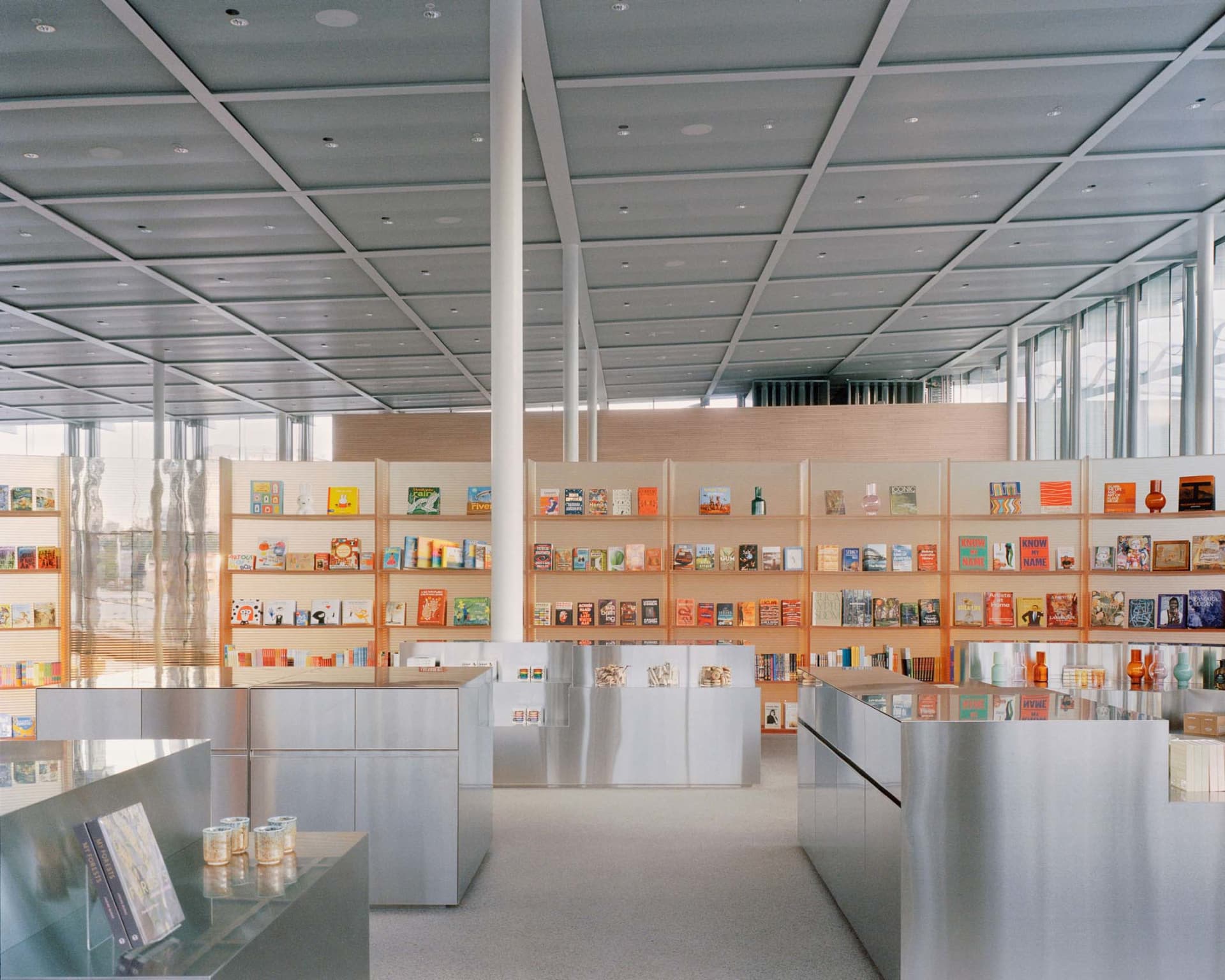 A modern bookstore with metal shelves displaying various books and products.