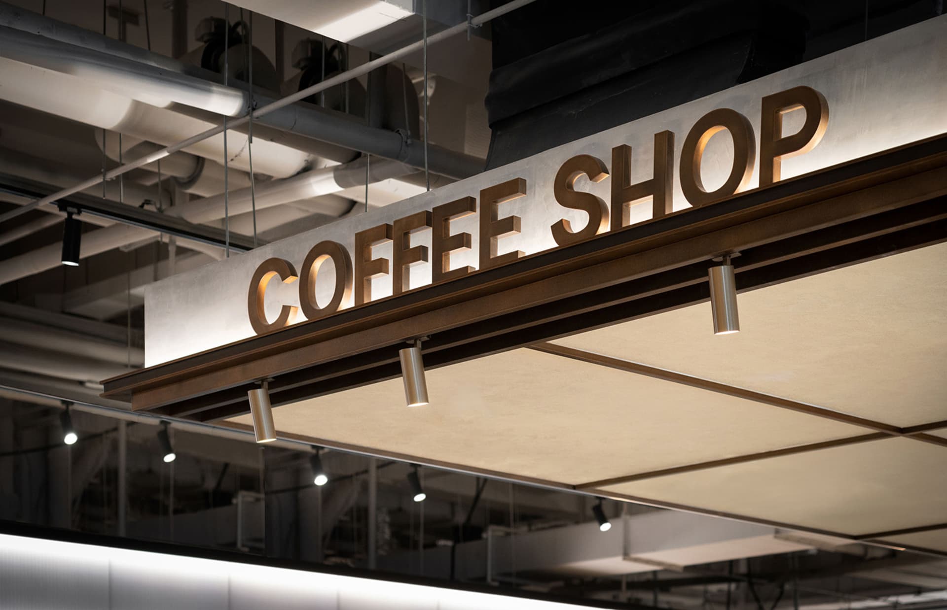 Modern, industrial-style coffee shop signage with metallic cladding.