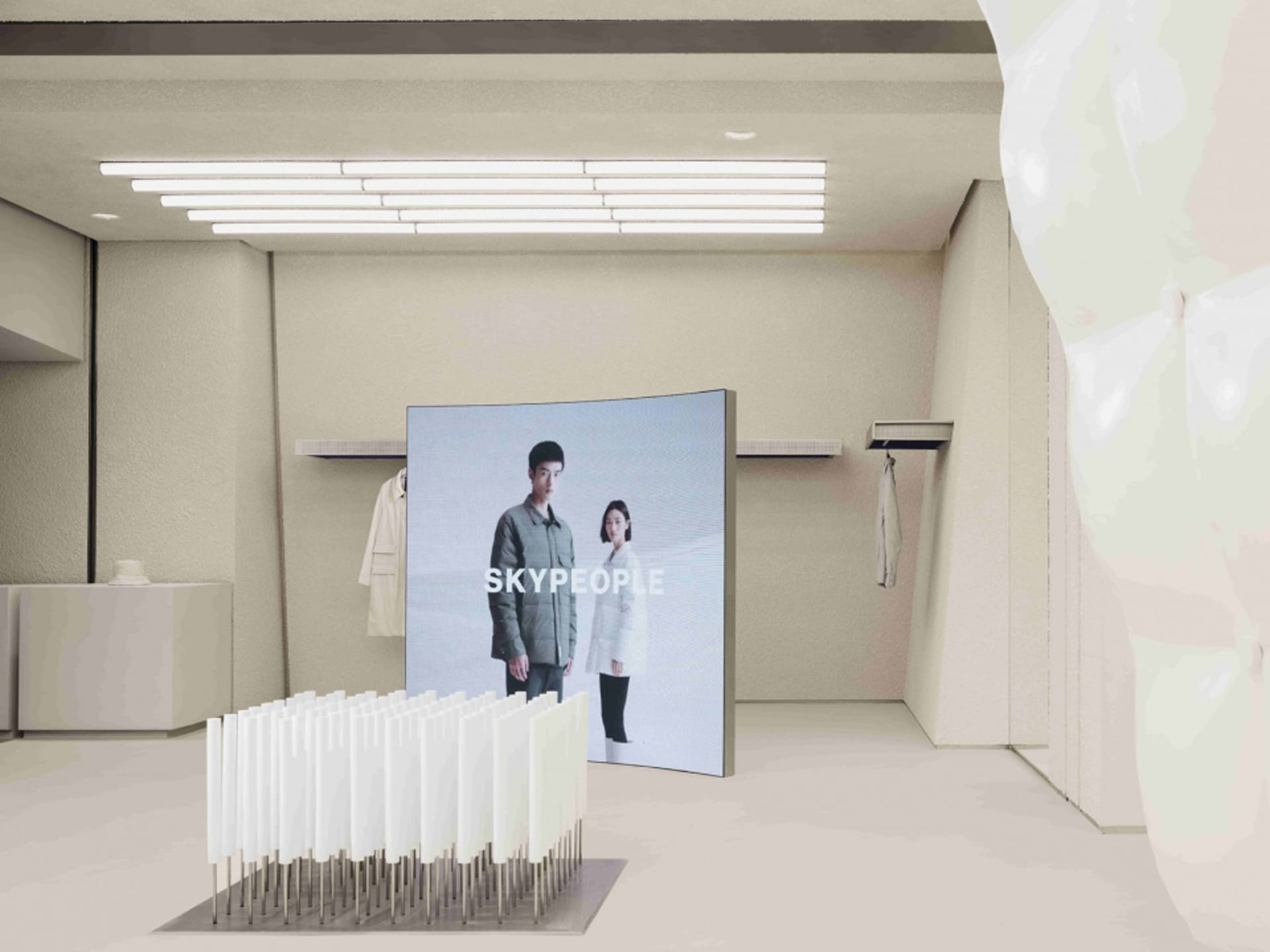 現代零售店面展示數位螢幕,螢幕上呈現兩位模特兒與品牌名稱「SKYPEOPLE」。