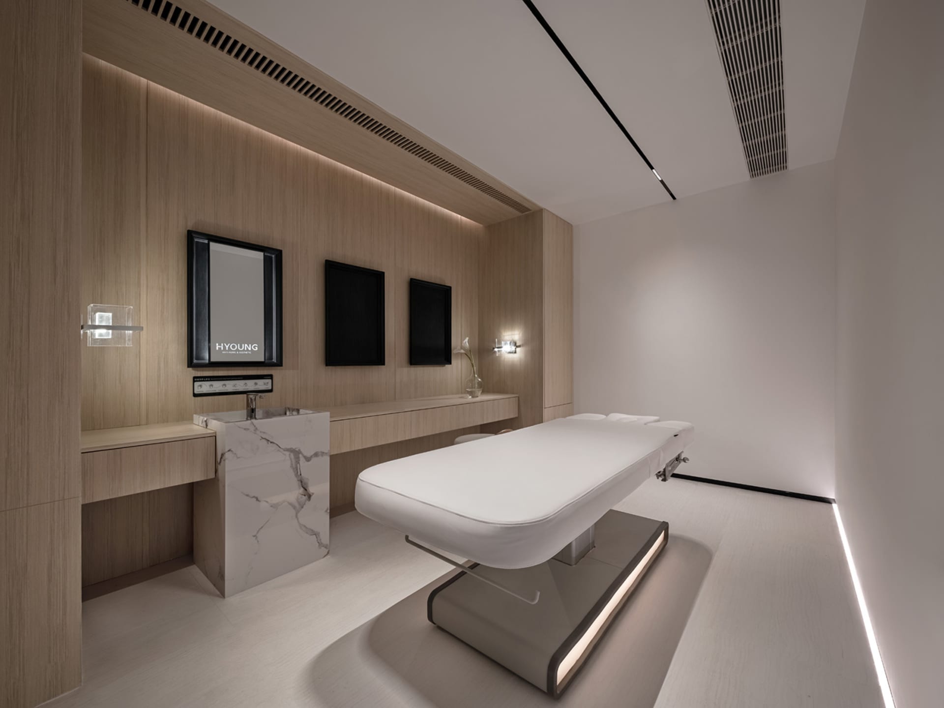 A minimalist medical room with wooden walls and a white bed.