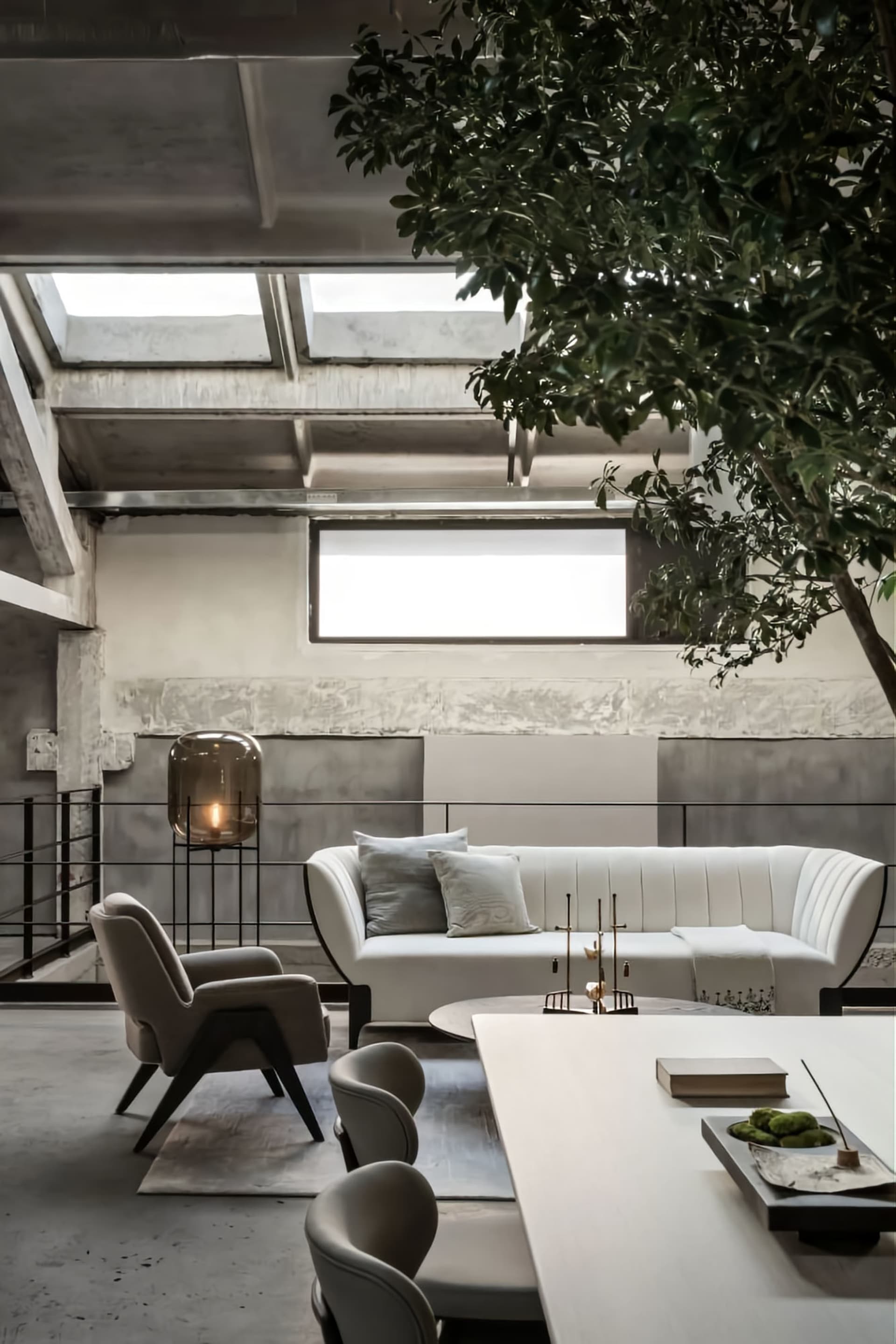 A modern living room with a white sofa, a white table, and a concrete floor, under skylights.