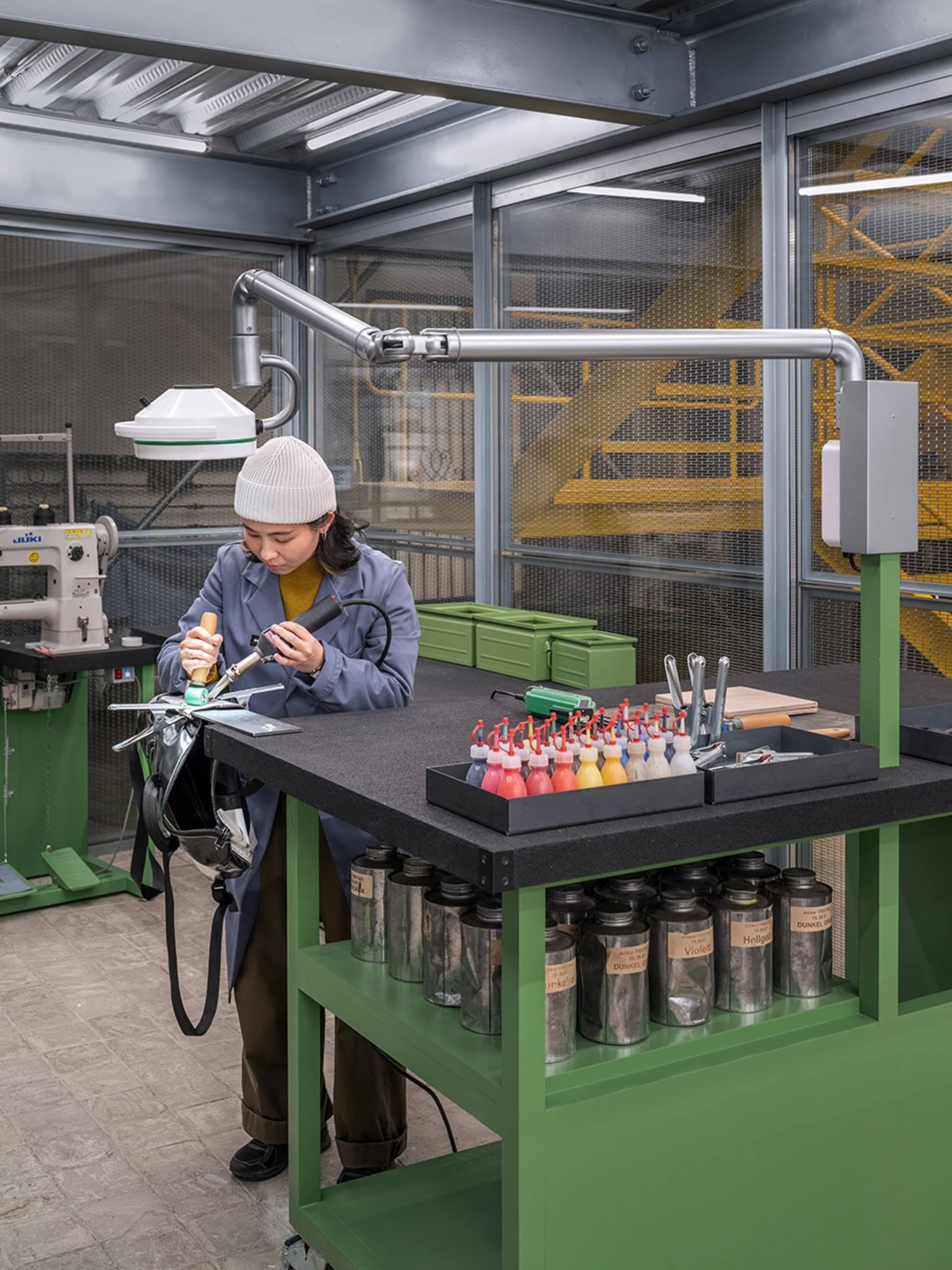 A woman in a workshop using tools and equipment on a table.