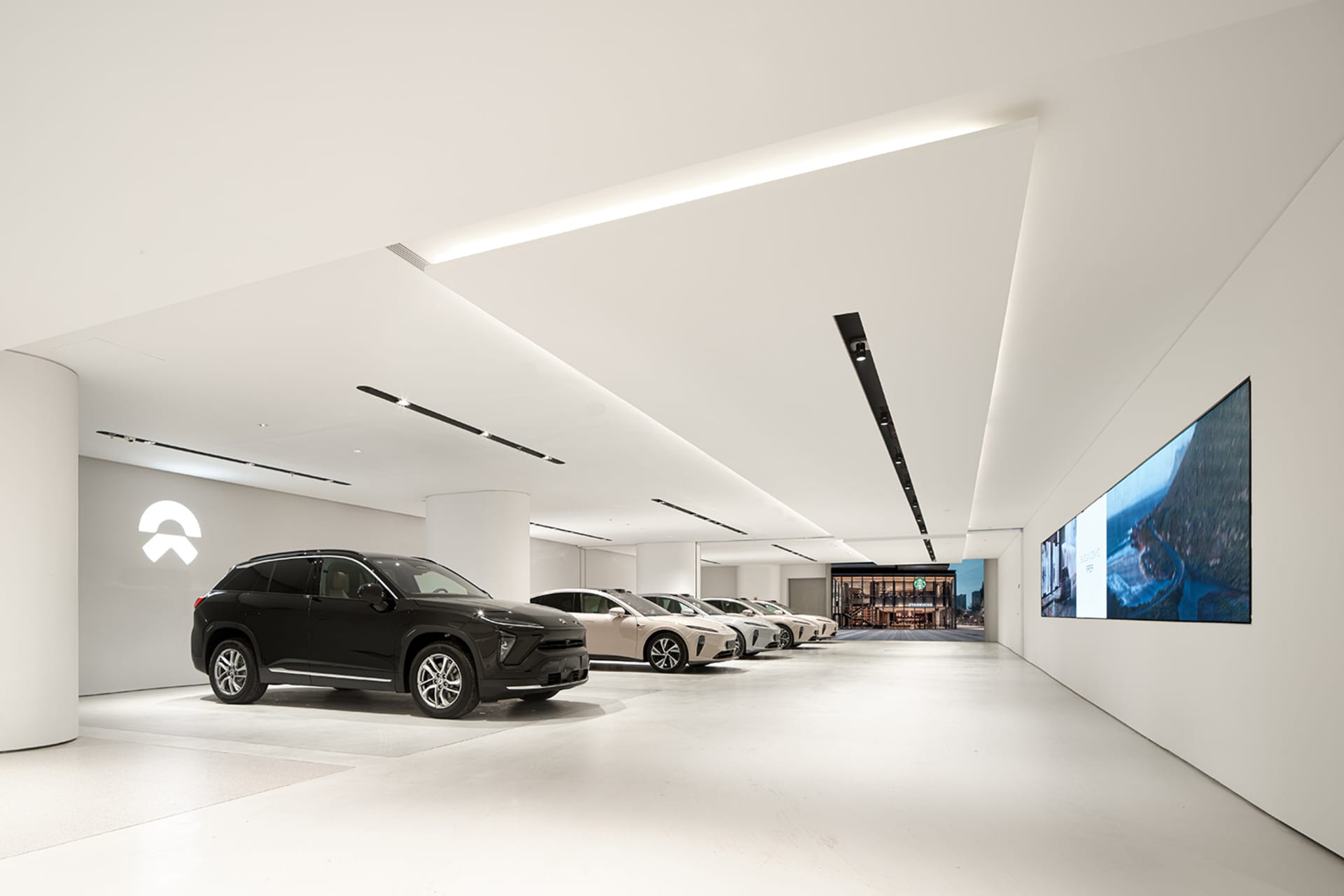 A modern car showroom with a minimalist, industrial design featuring concrete floors and LED lighting.