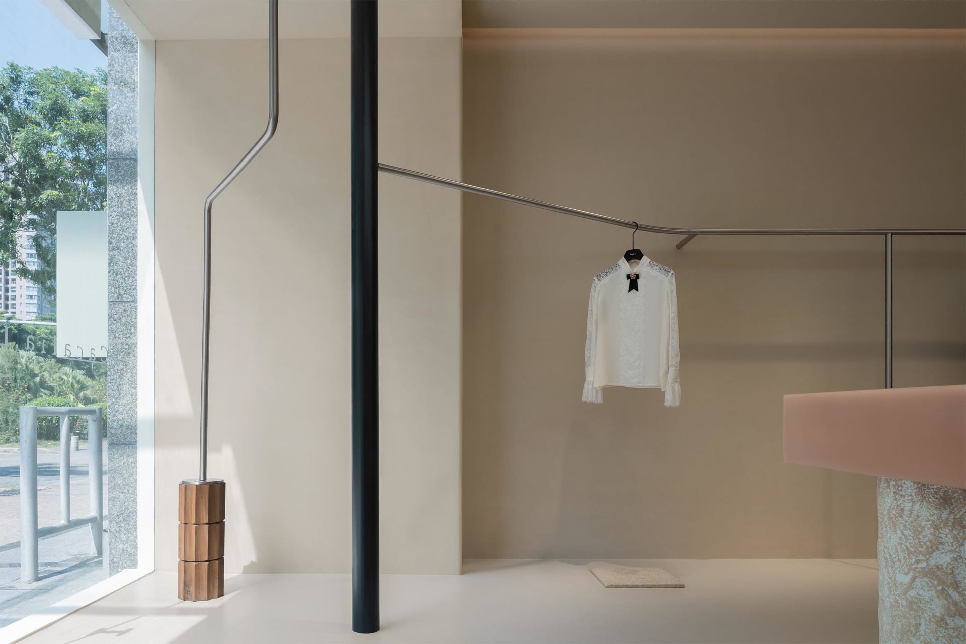 Modern clothing store interior with minimalist design and metal clothing rod display.