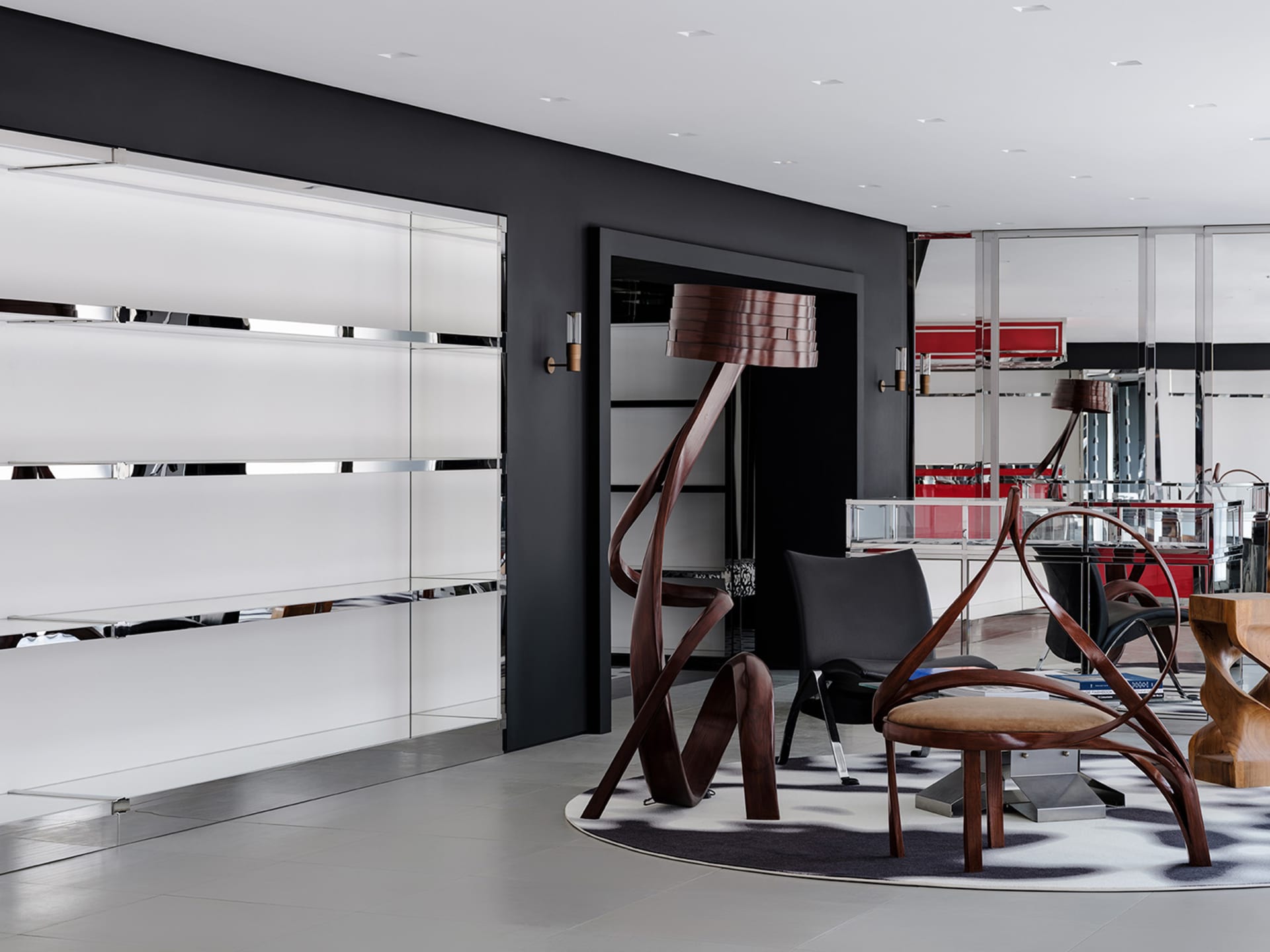 A modern lobby featuring sleek wooden and metal furniture with a glass element, set against a black and white geometric patte