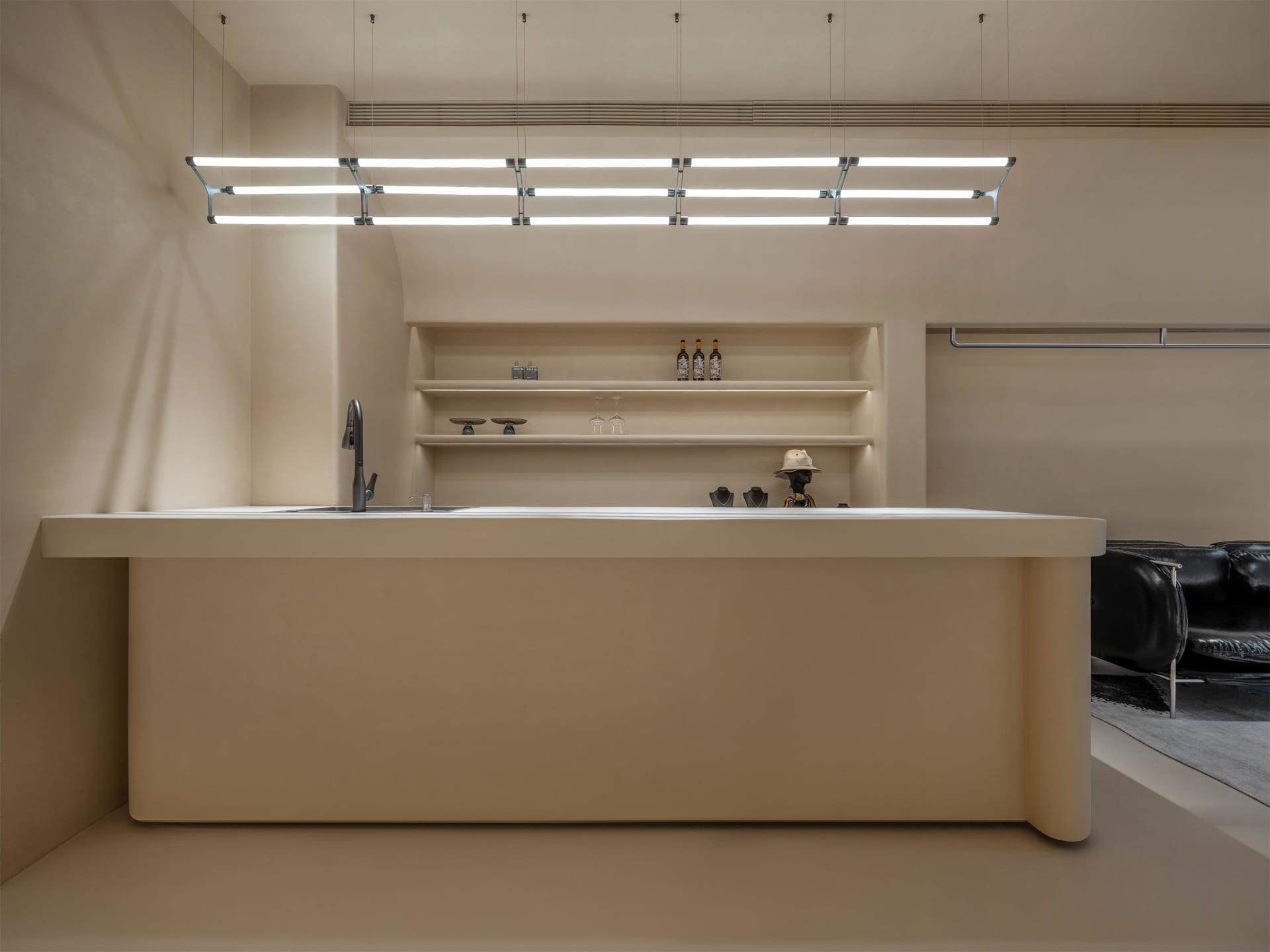 Minimalist kitchen with concrete island, sink, and shelves.