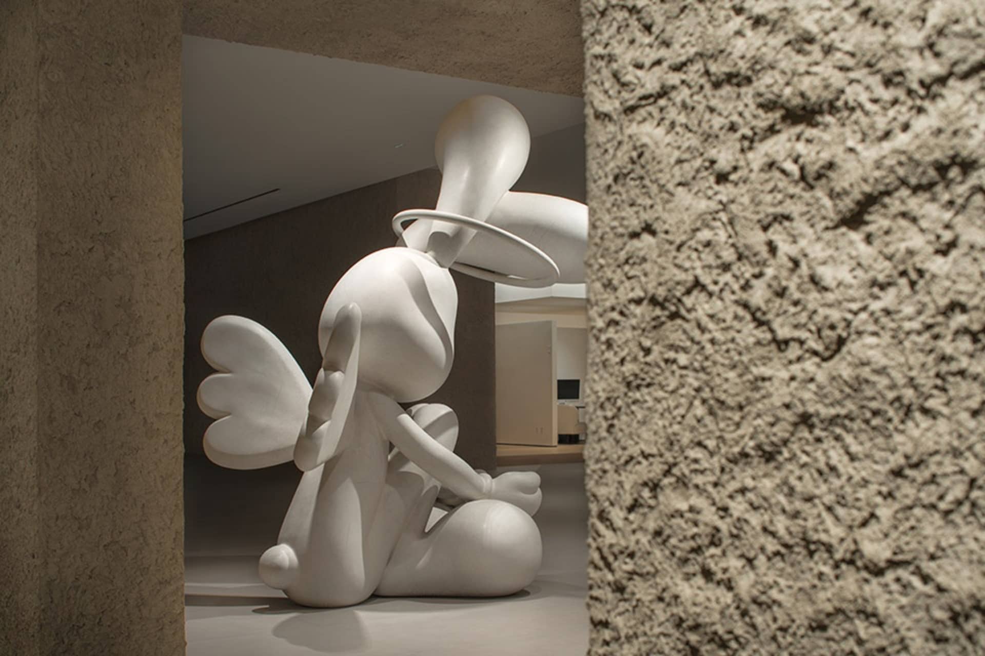 A minimalist plaster sculpture with a halo and wings in a modern design setting.