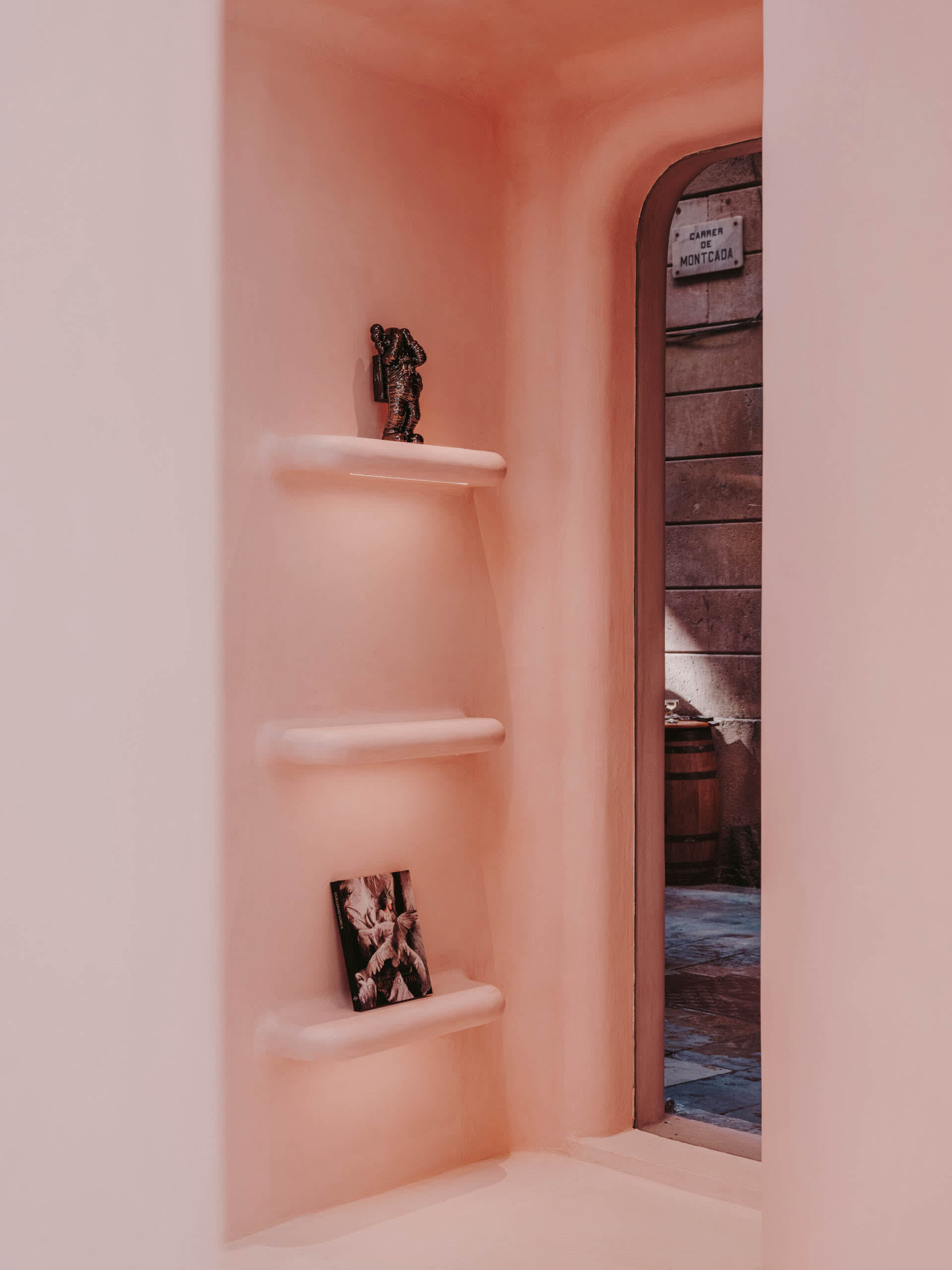 A minimalist concrete shelving unit with decorative items in a cozy alcove.