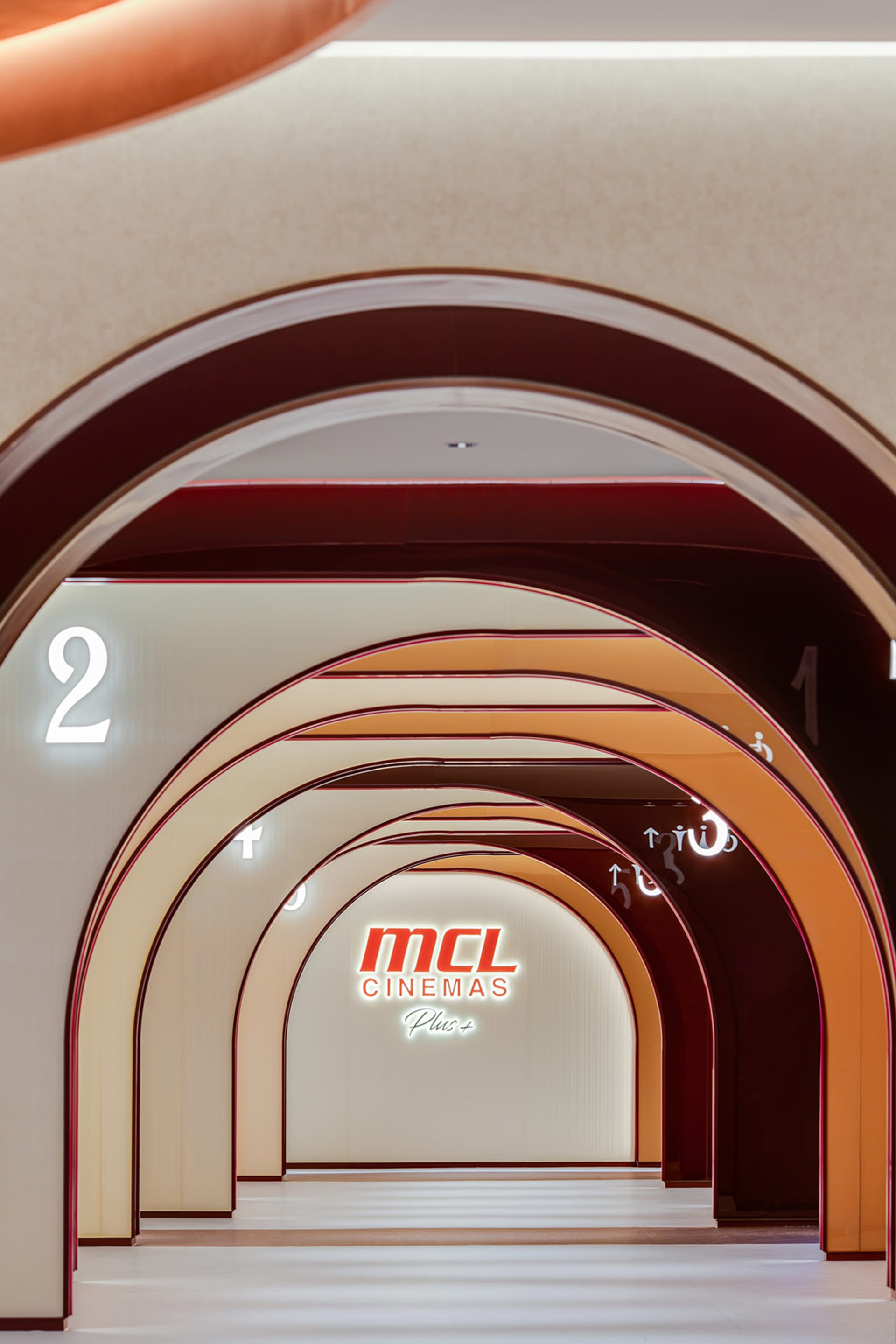 A modern cinema interior with illuminated signs and archways.