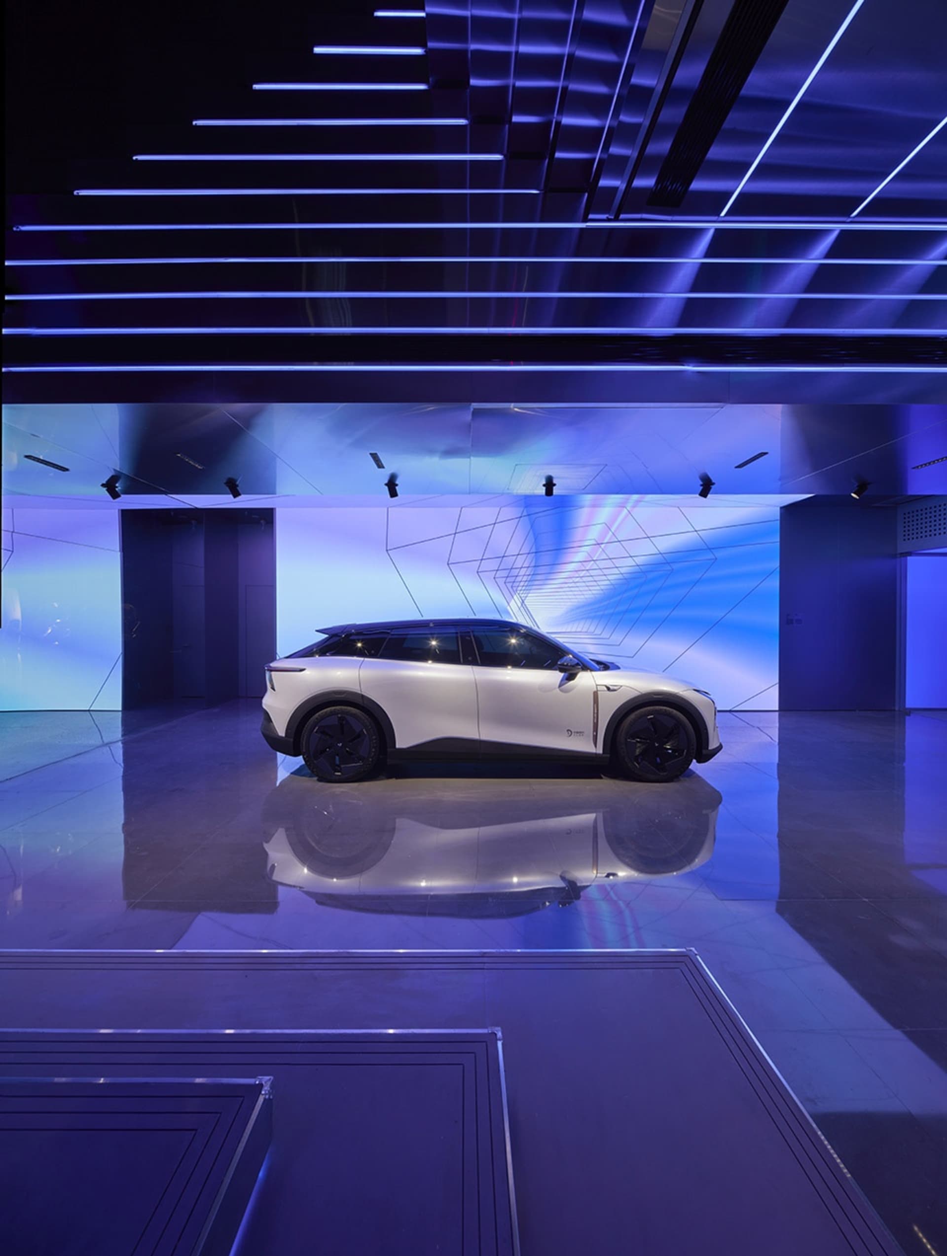 A sleek, white car displayed at a launch event with a futuristic interior and exterior design.
