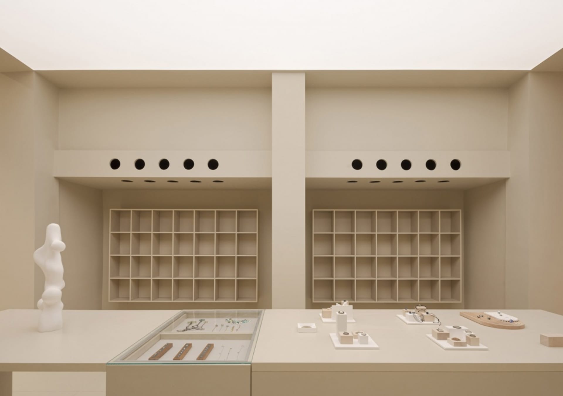 A minimalist retail jewelry shop featuring modern fixtures and shelves with neutral-toned finishes.