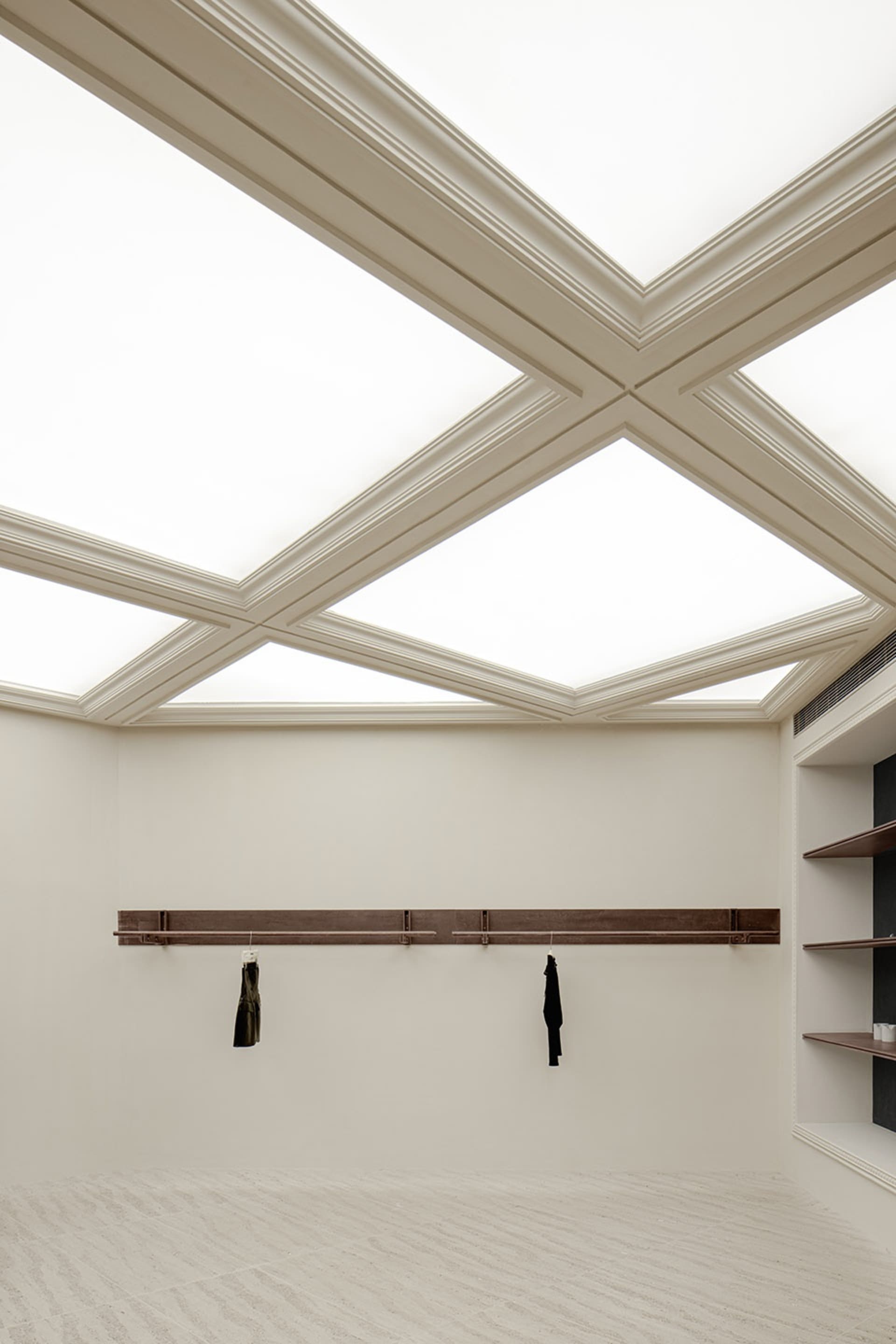 A spacious, modern interior with a unique triangulated ceiling design, featuring abundant natural light.