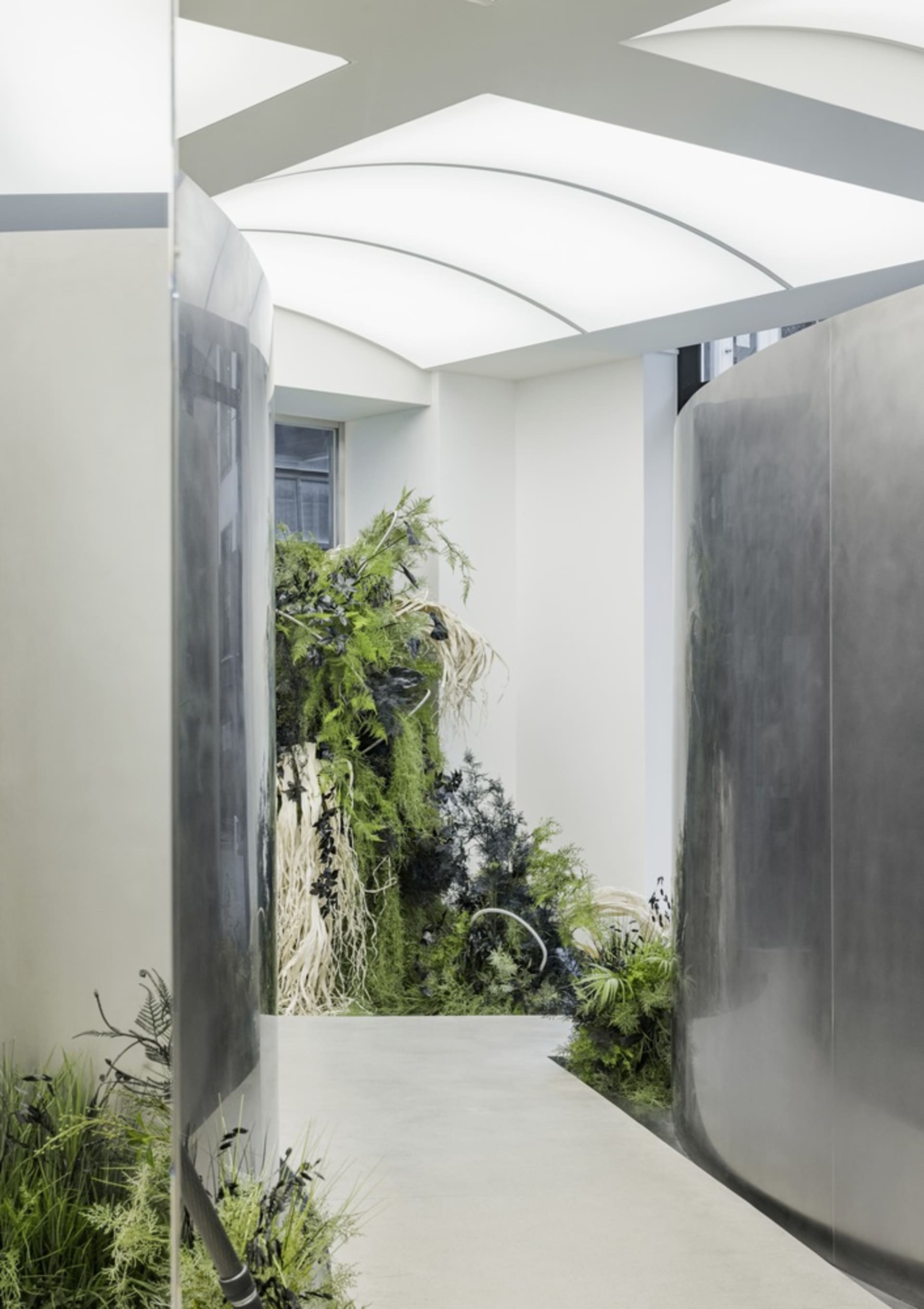A modern hallway with dark metallic walls featuring lush green plant walls