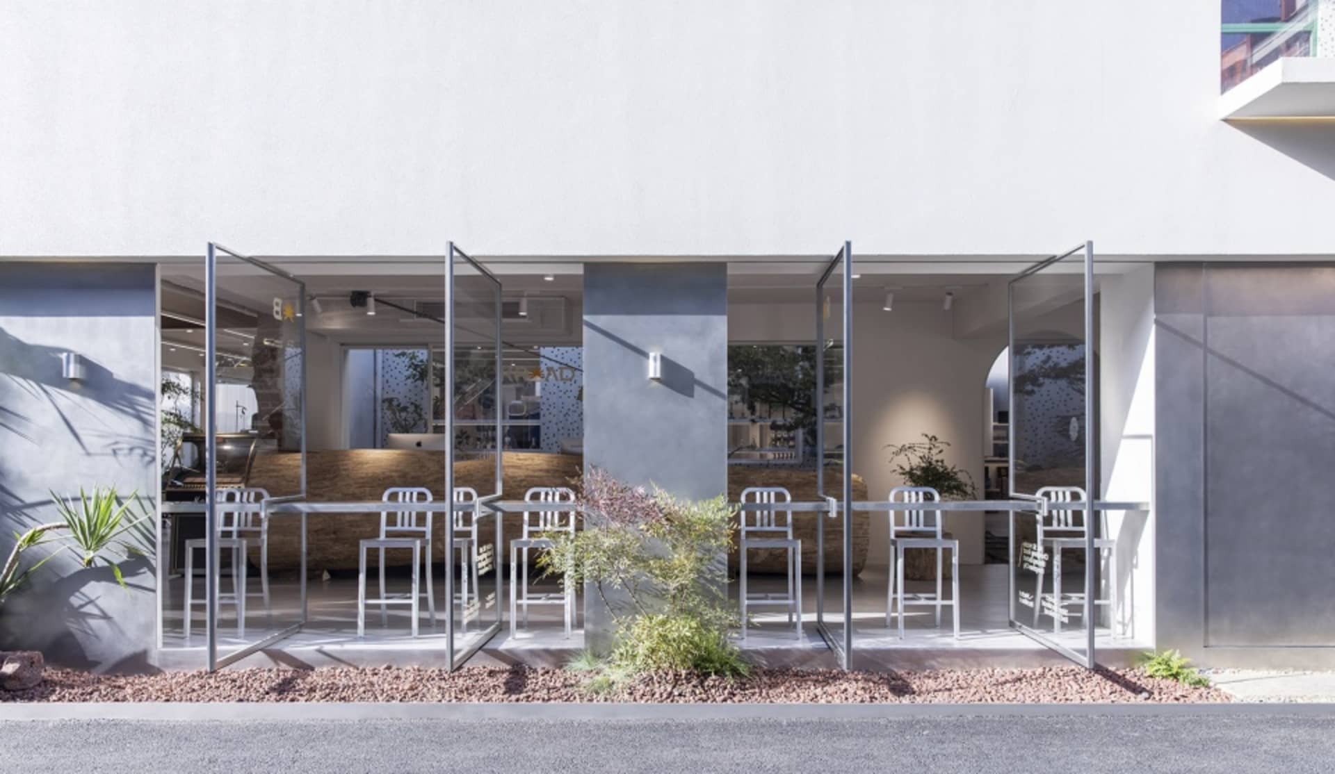 Modern glass and metal storefront of a coffee shop with concrete accents.