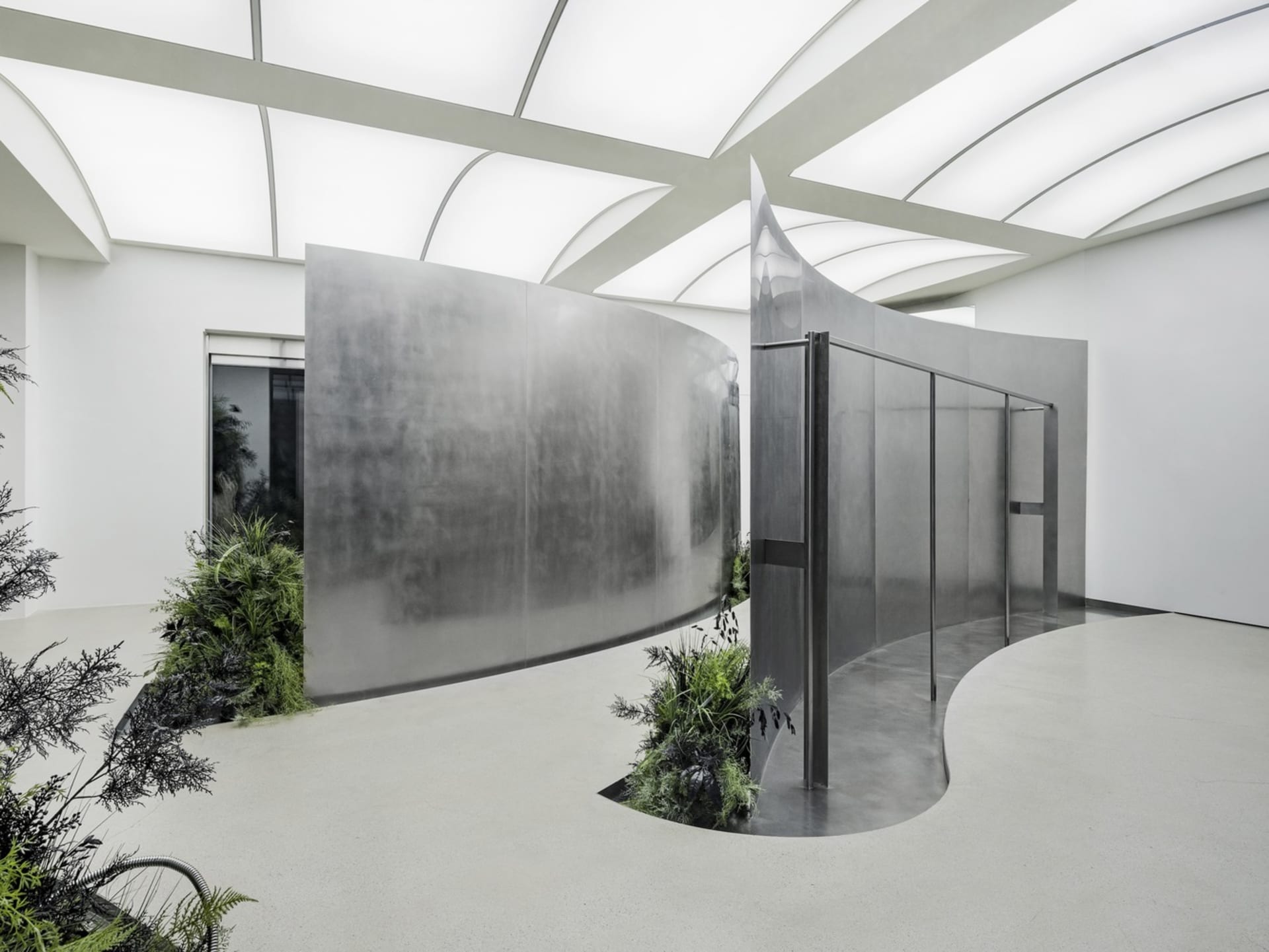 A modern, metal-walled architectural installation with green plants.