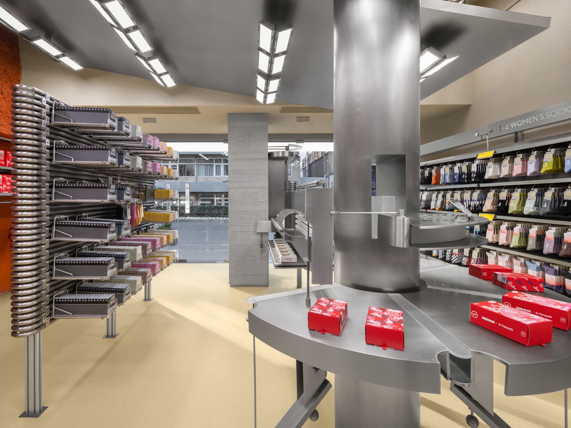 Modern retail space featuring steel shelves and a central pod with red boxes.