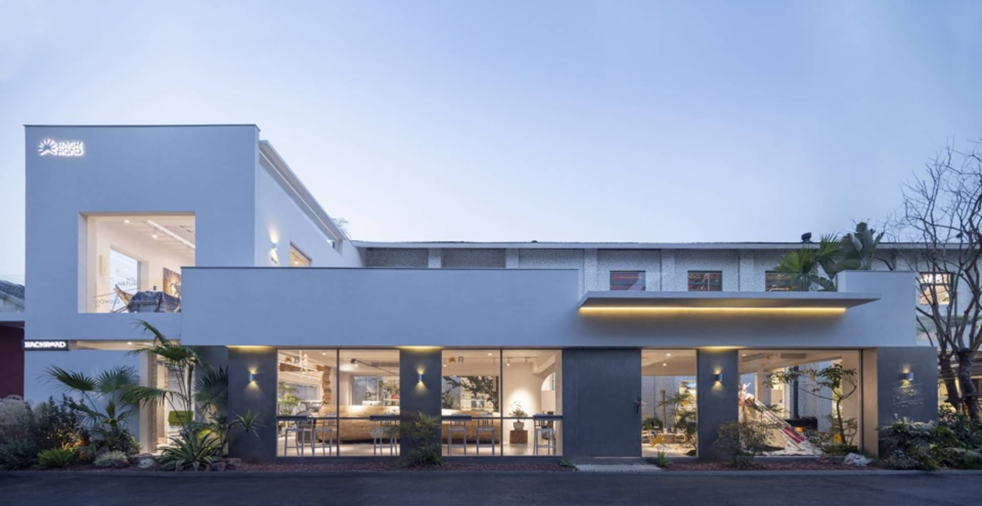 A modern storefront with a concrete facade and large windows, featuring a white and gray color palette.