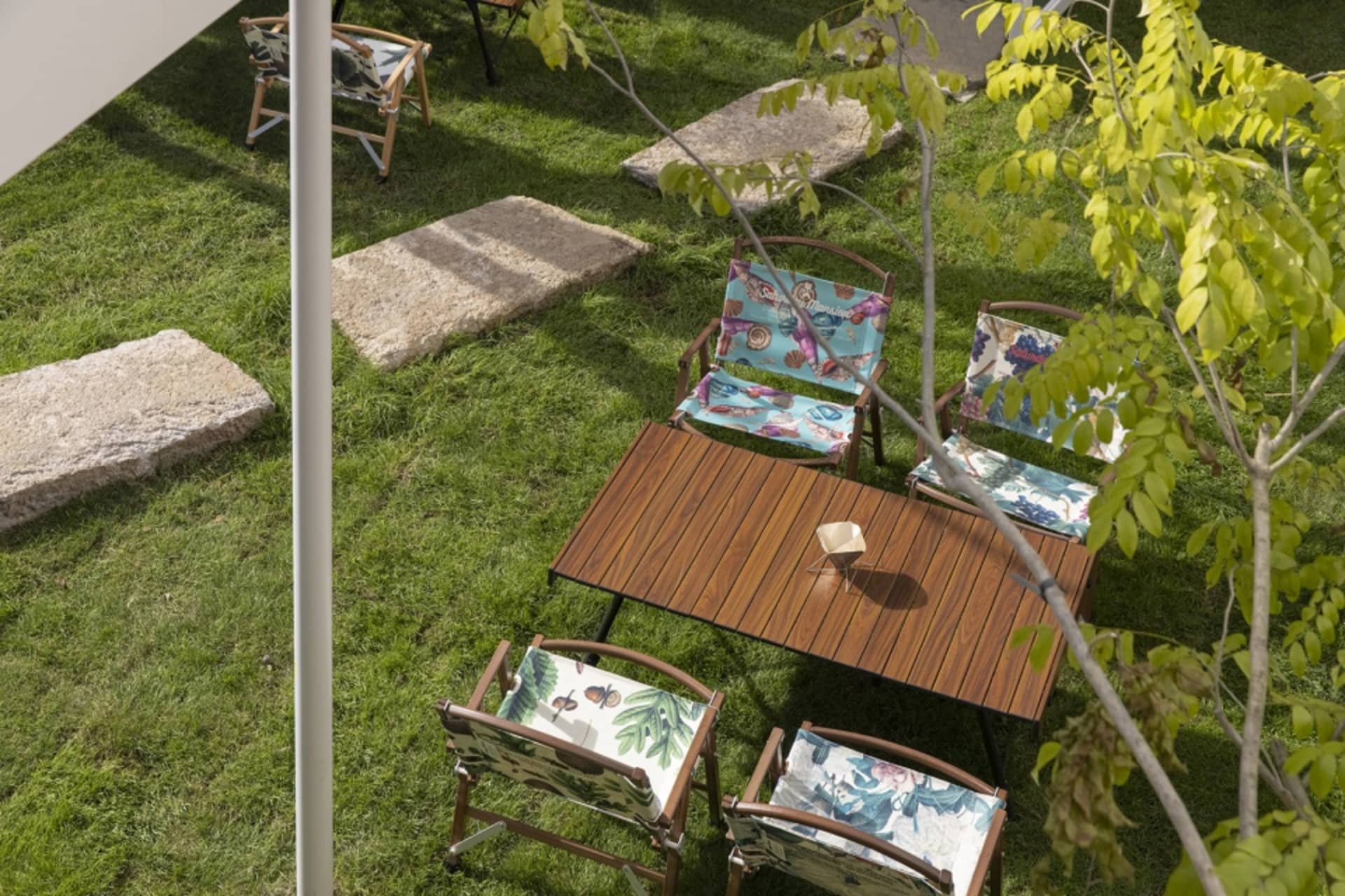 Outdoor furniture set in a garden setting with wooden table and patterned chairs.