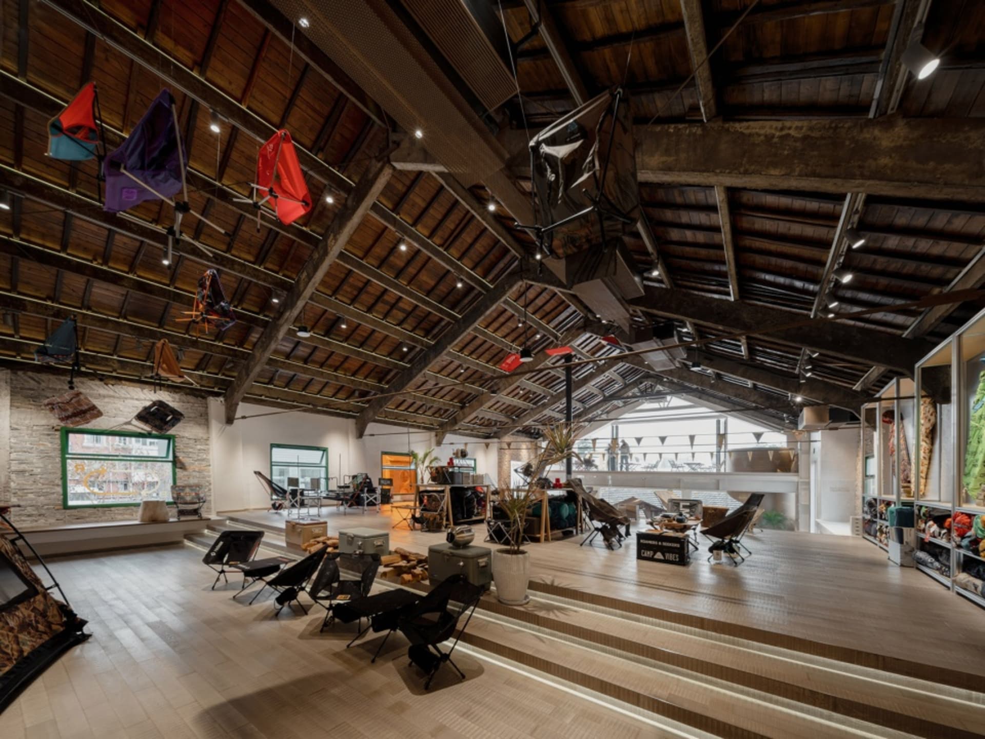 A spacious industrial showroom with wooden floors, metal and glass displays, and concrete elements.