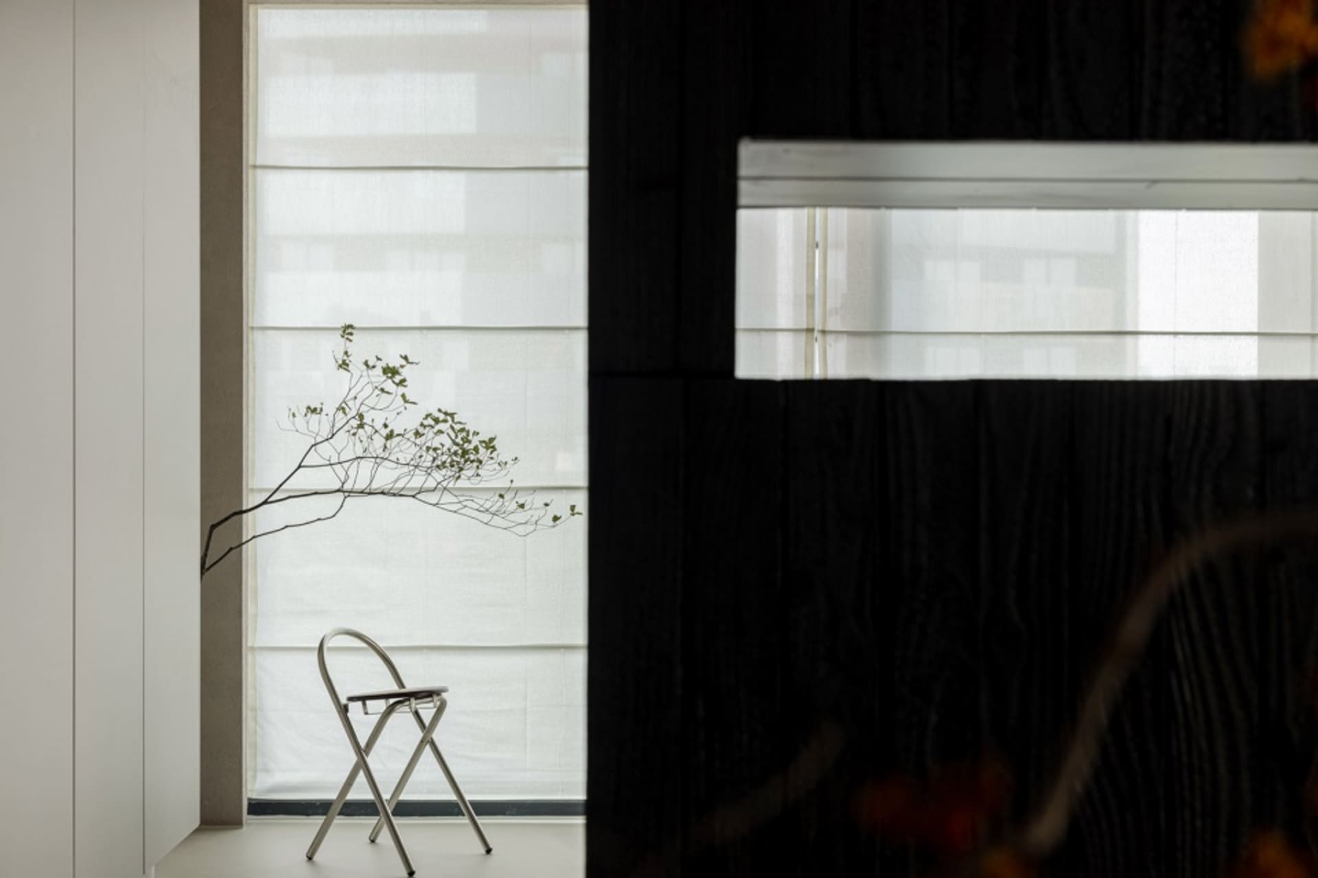 A minimalist bedroom with a modern metal chair and minimalist decor.