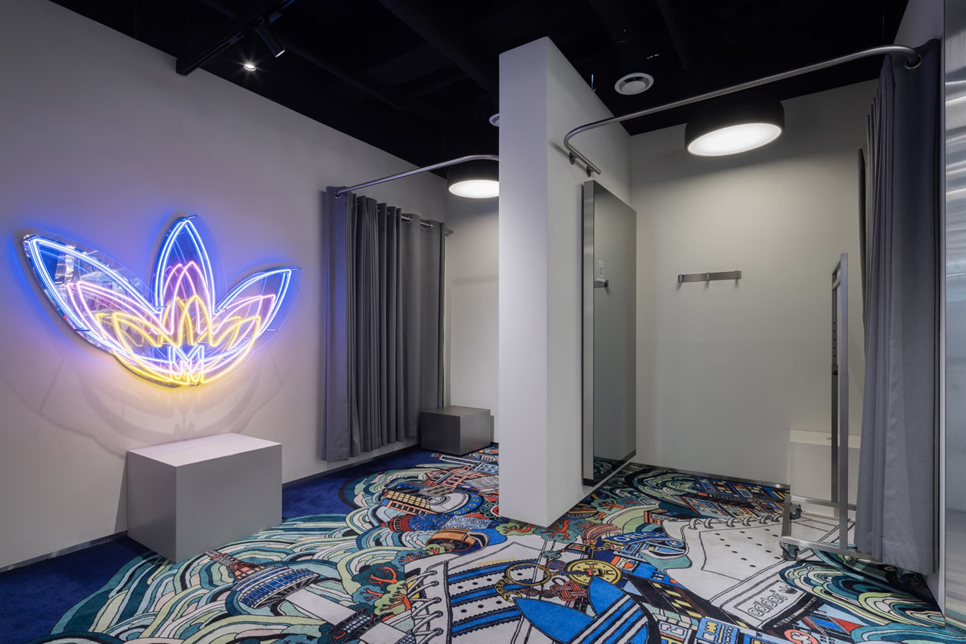 A well-designed retail shop with a concrete floor and illuminated neon art on the walls.