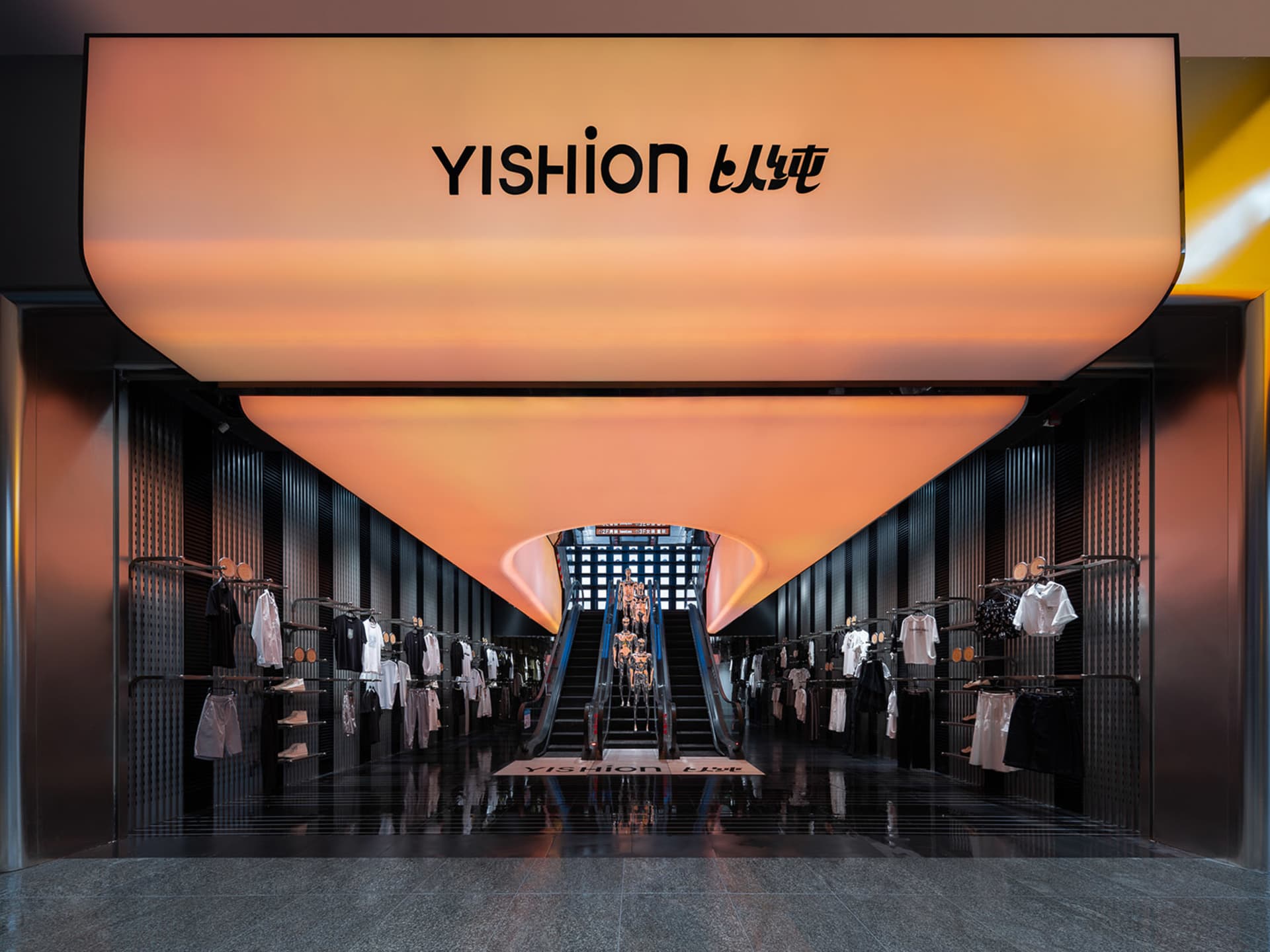 Modern retail space with a Yishion clothing store, featuring glass walls, metal railings, and concrete flooring.