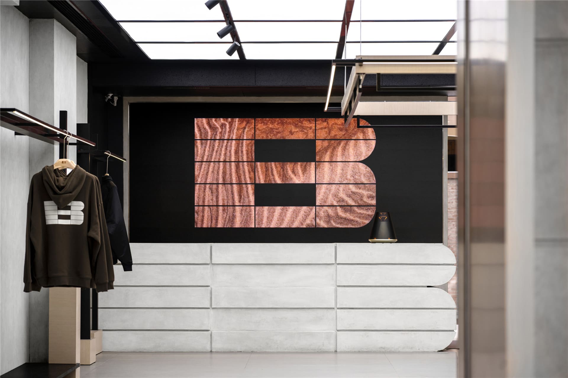 Modern retail storefront with concrete facade and large wooden logo on black background
