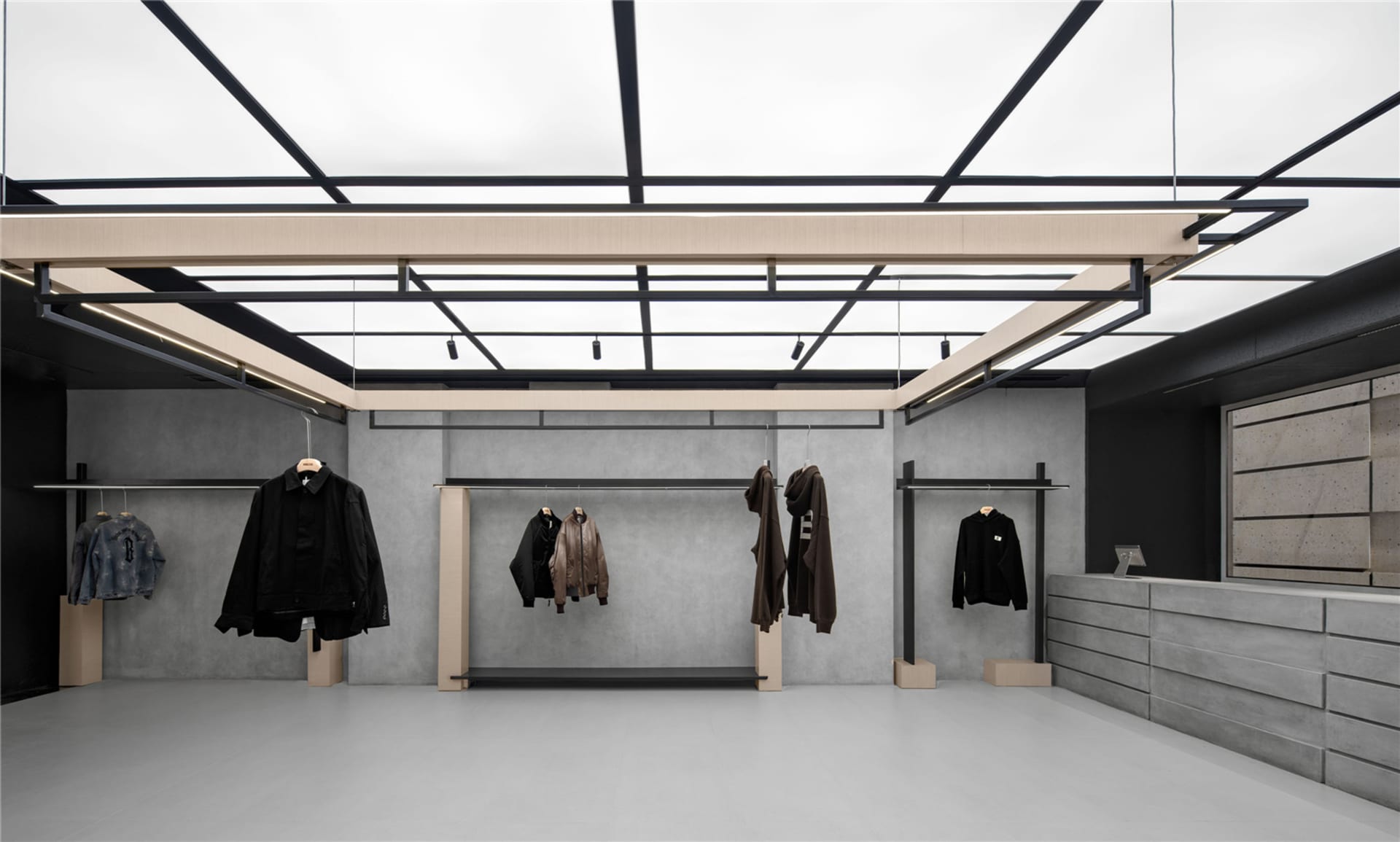 A minimalist retail shop with concrete walls, black metal hangars, and hanging clothing.