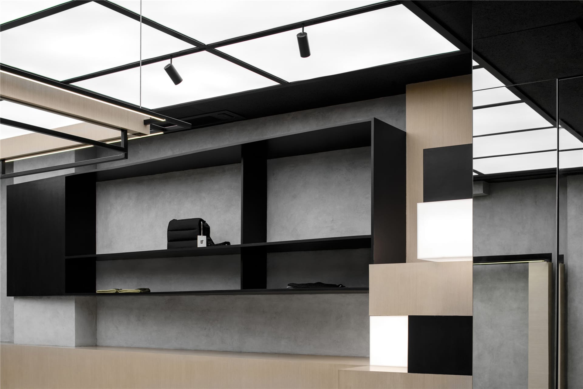 An office reception area featuring modern design elements such as black metal shelves, concrete walls, a blending cube instal