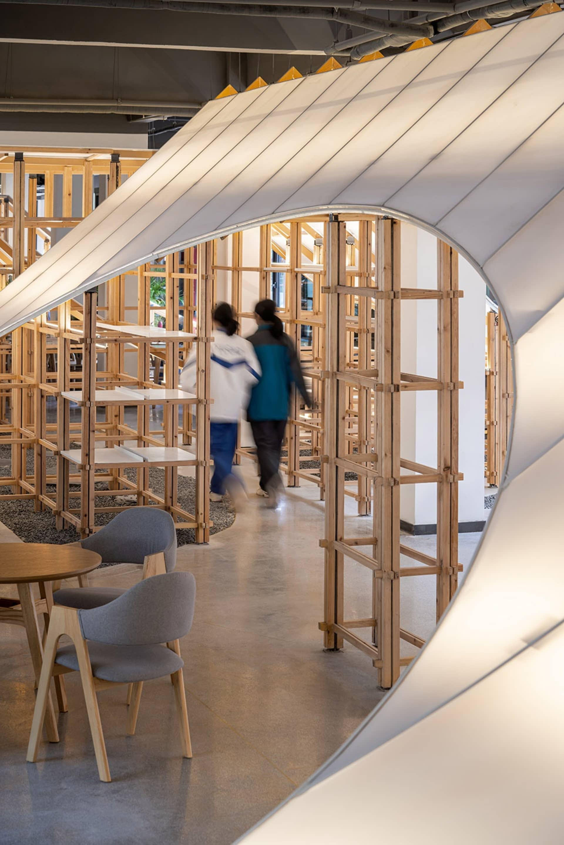 Interior of a modern industrial office space with wooden furniture and exposed structural elements.