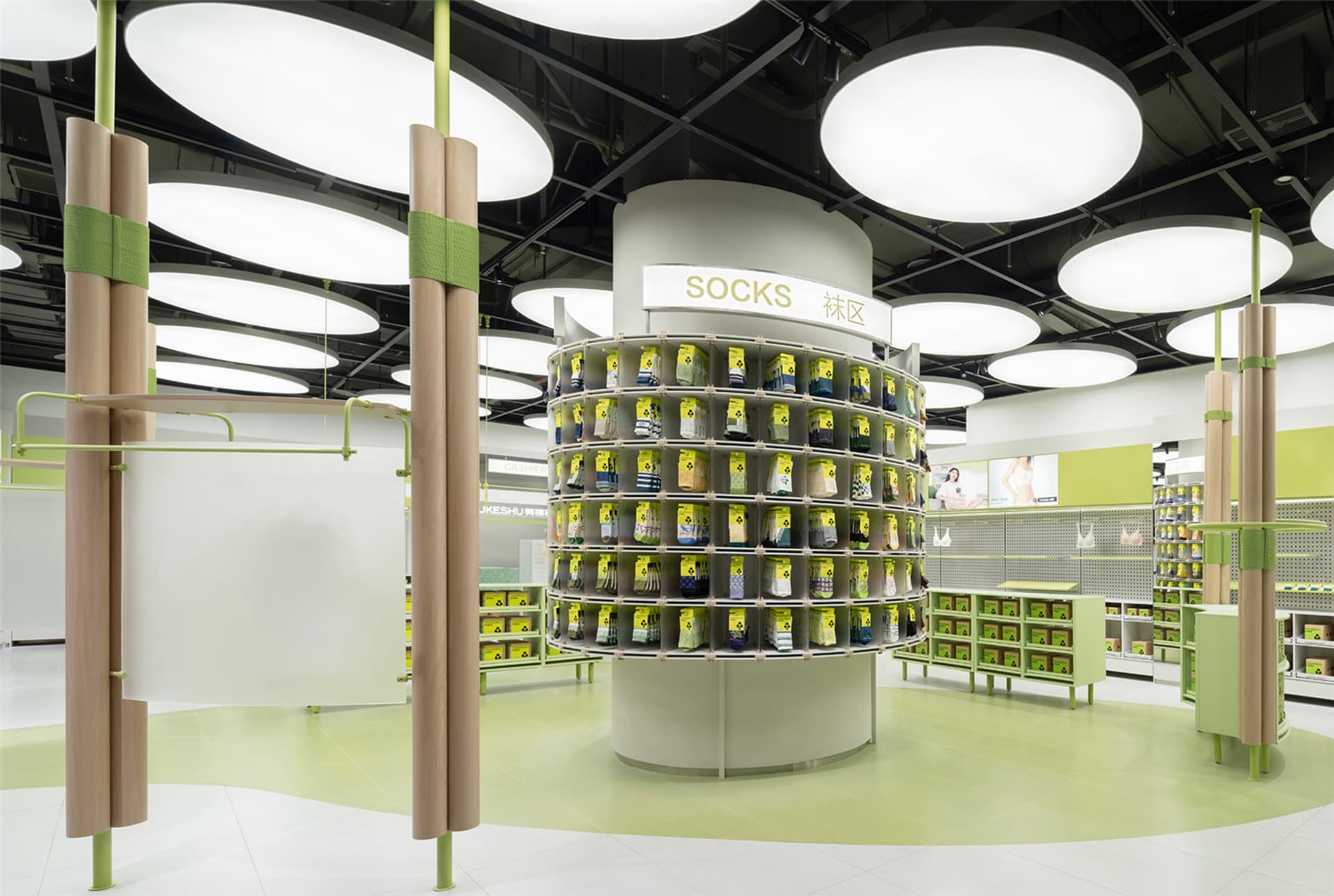 A well-lit, modern retail shop displaying various products on a round shelving unit with a sign labeled 'Socks'.