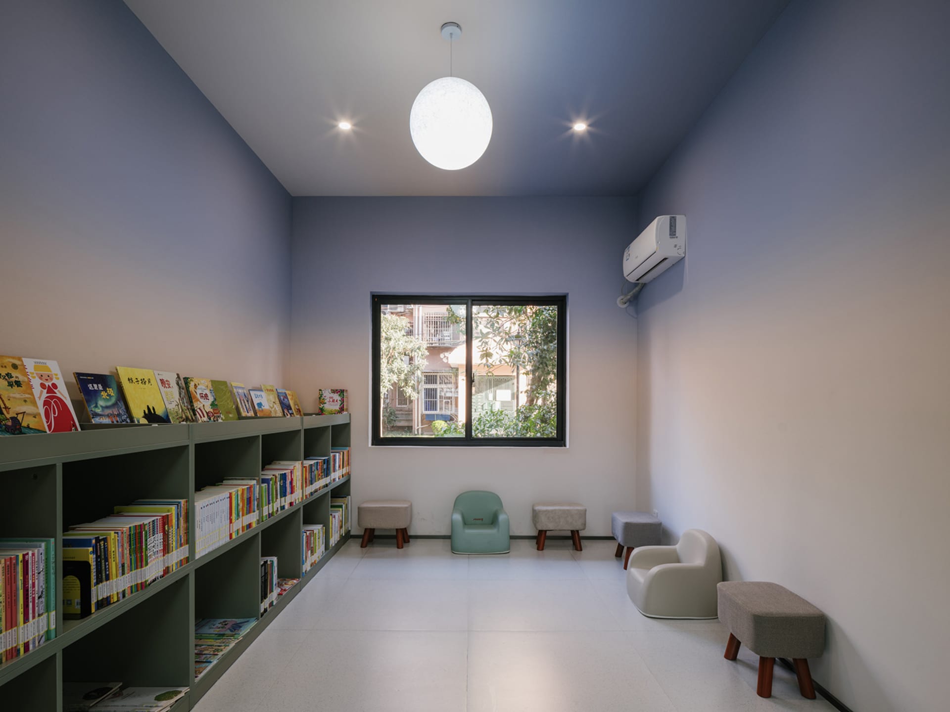 A minimalist reading room with concrete walls, wooden furniture, and a bookshelf filled with books.