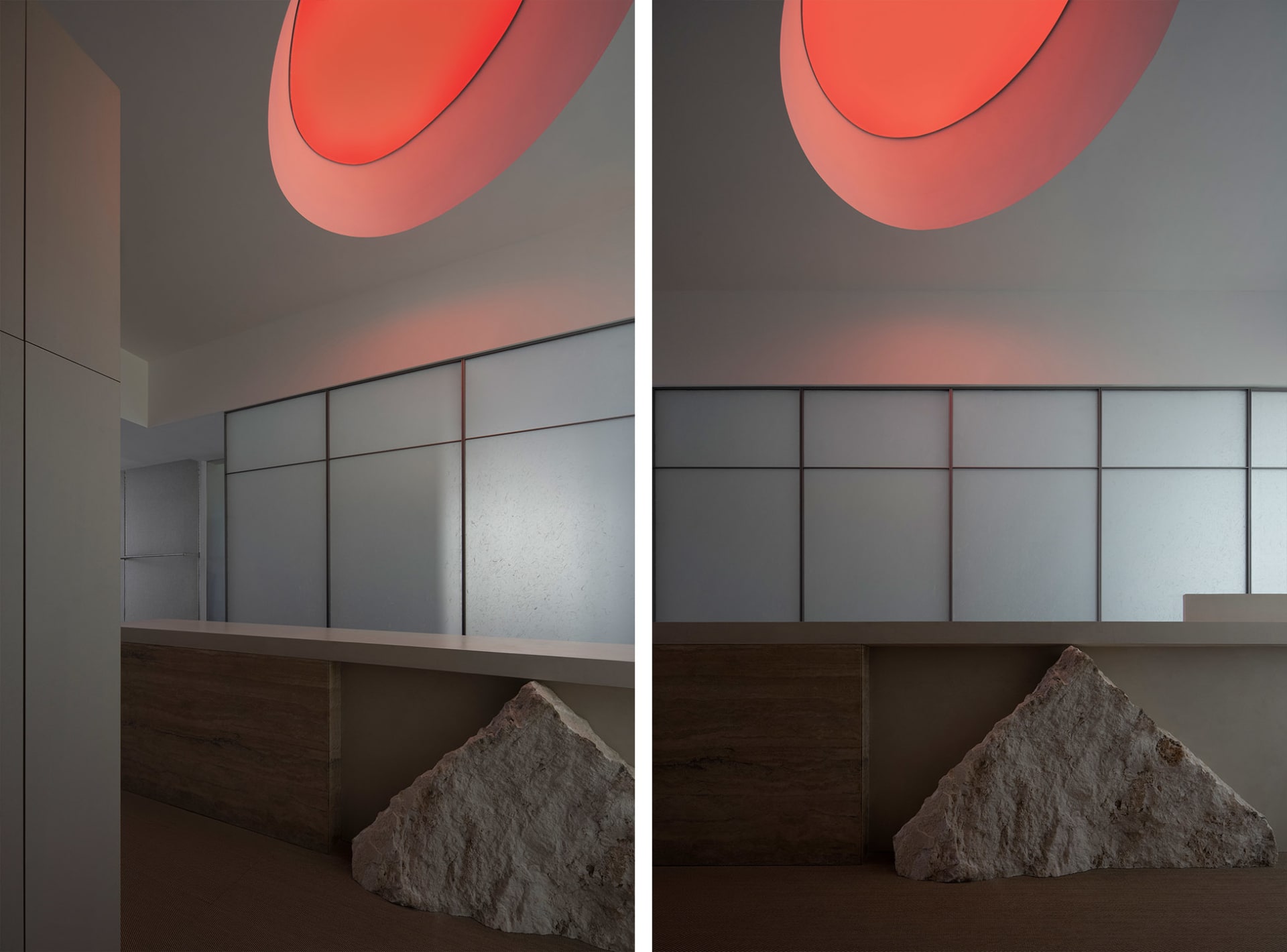 Modern hotel lobby with glass partitions and marble walls illuminated by orange circular lights.