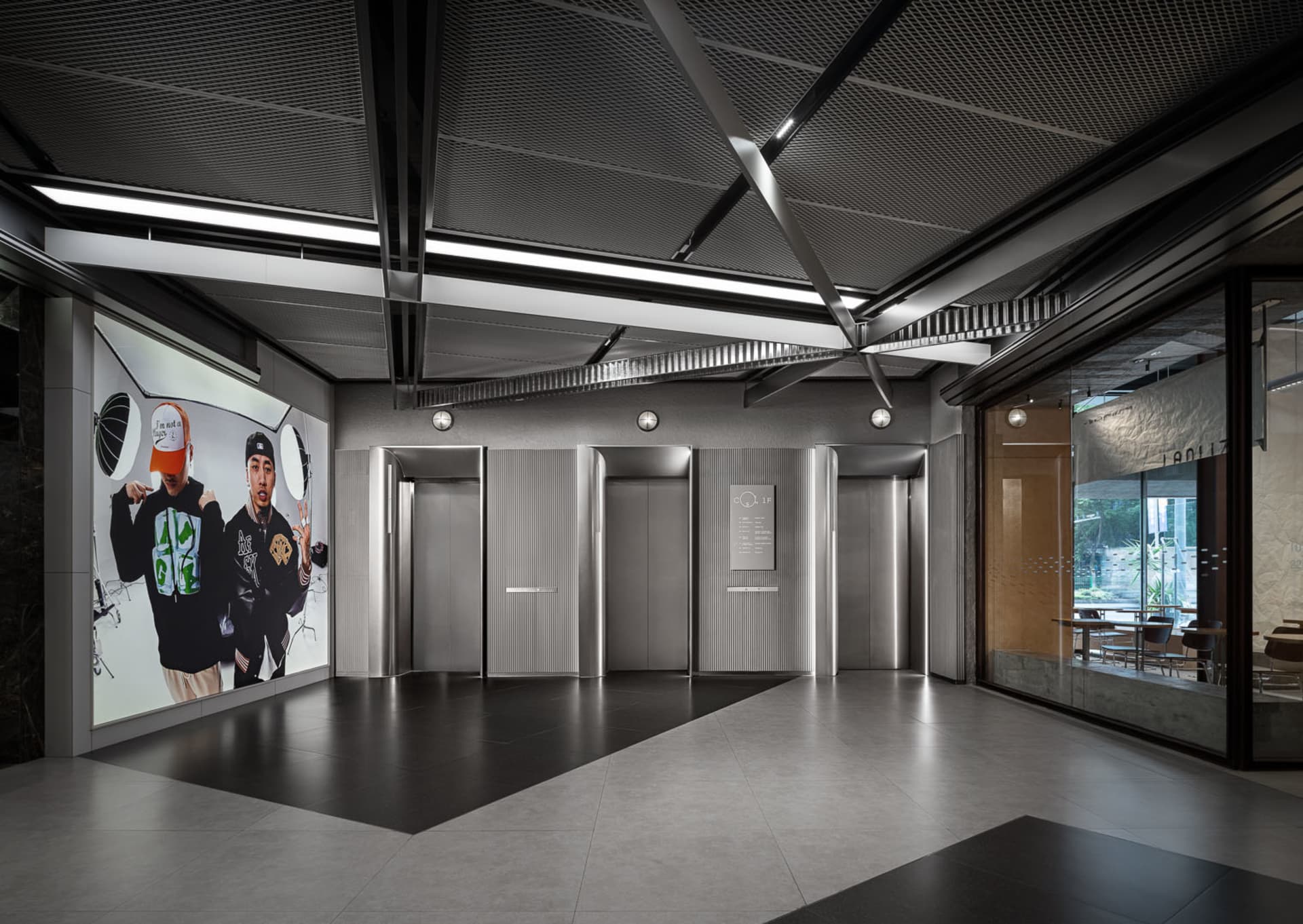 Modern industrial-style lobby with concrete, metal, and glass elements.