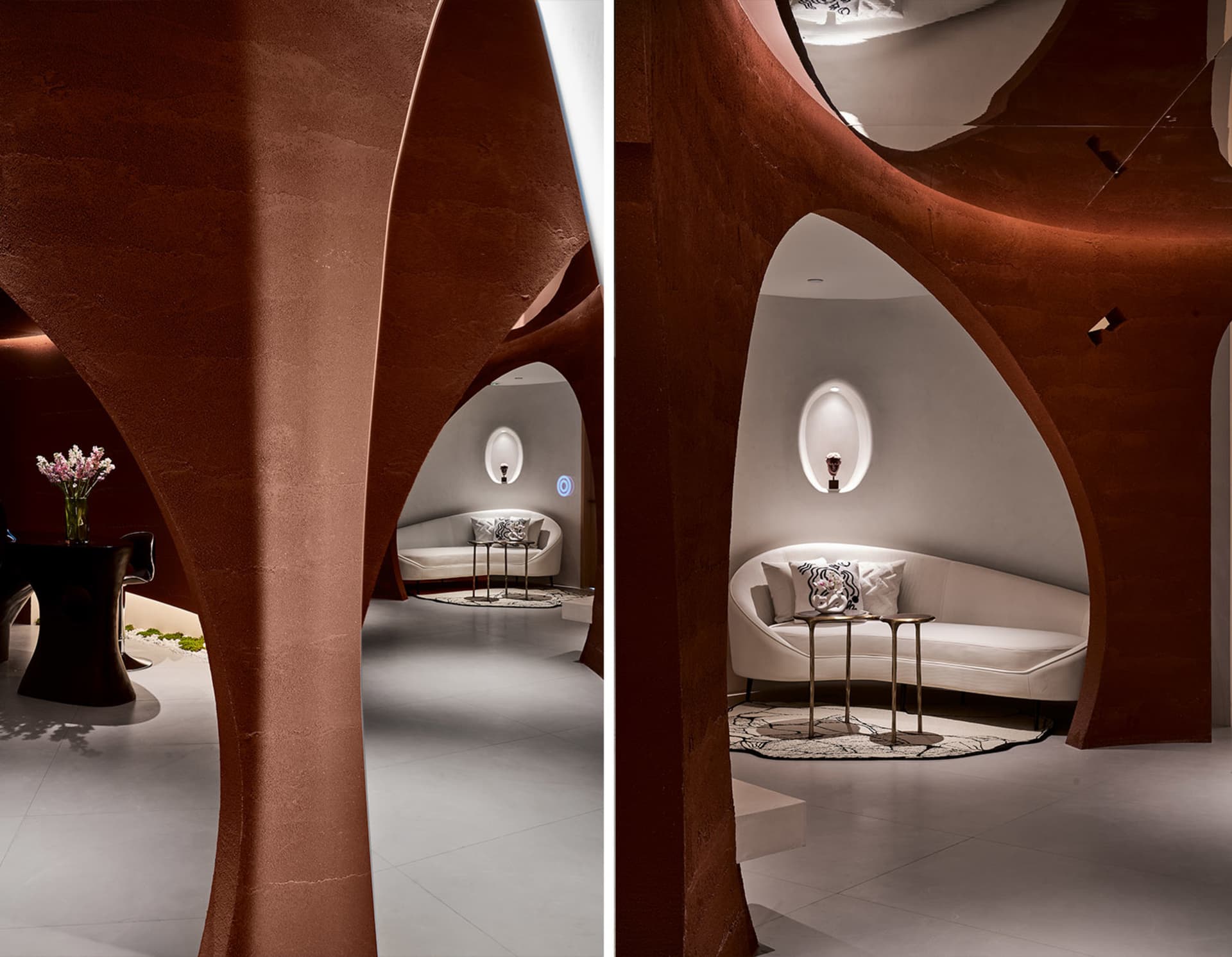 A modern living room featuring white sofas, tables, and a geometric concrete archway with ambient lighting.