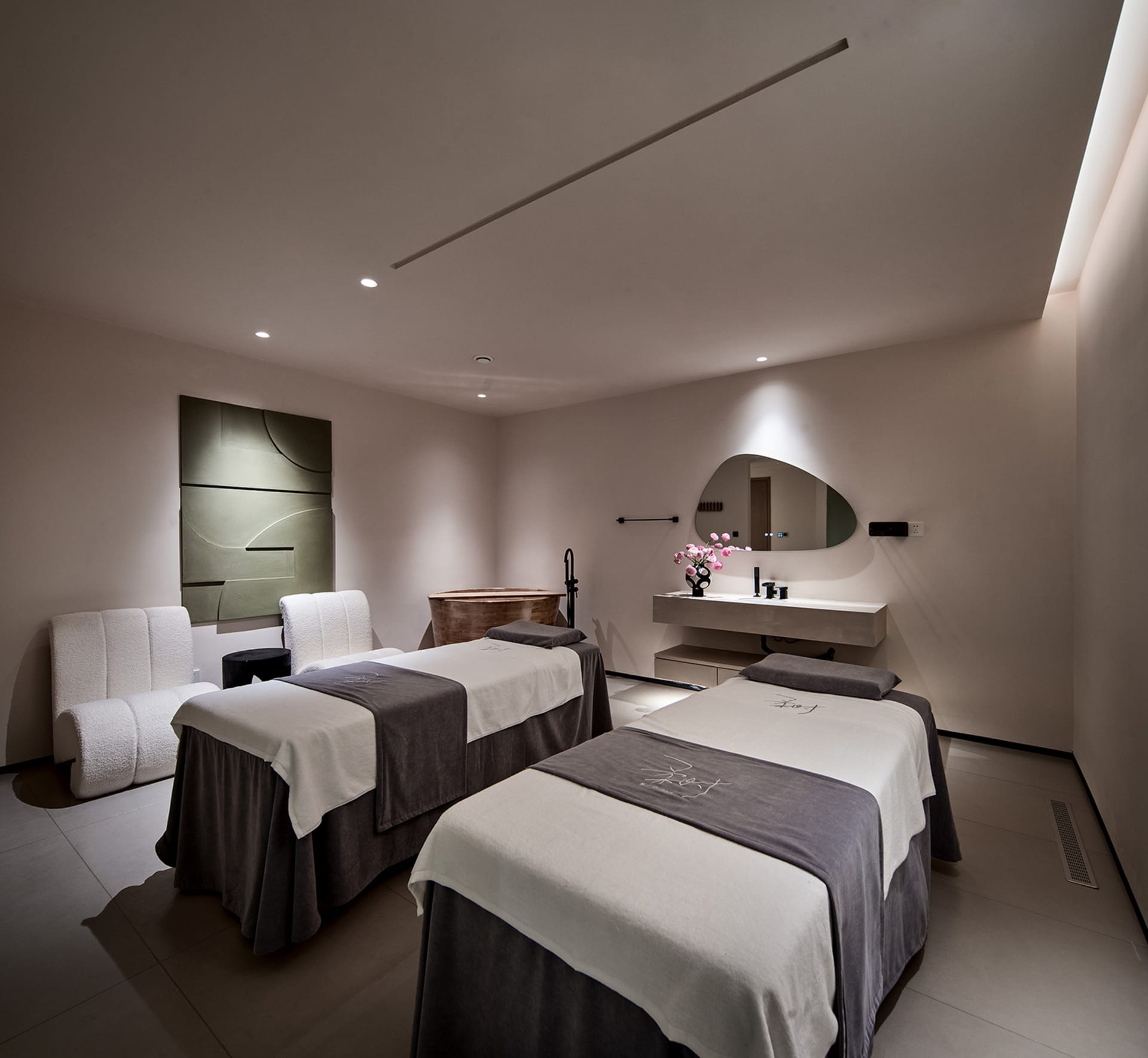 Spa treatment room with two massage tables, modern decor, and white walls.